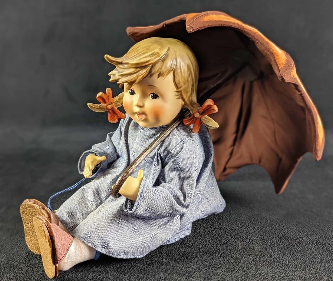 Vintage Goebel Hummel Girl Doll With Umbrella: Danbury Mint. Beautiful M.I. Hummel Doll, â€œUmbrella Girl.”The doll is about 8” high in a sitting position. Fine porcelain head, arms, and legs with a stuffed cloth body. Exquisitely