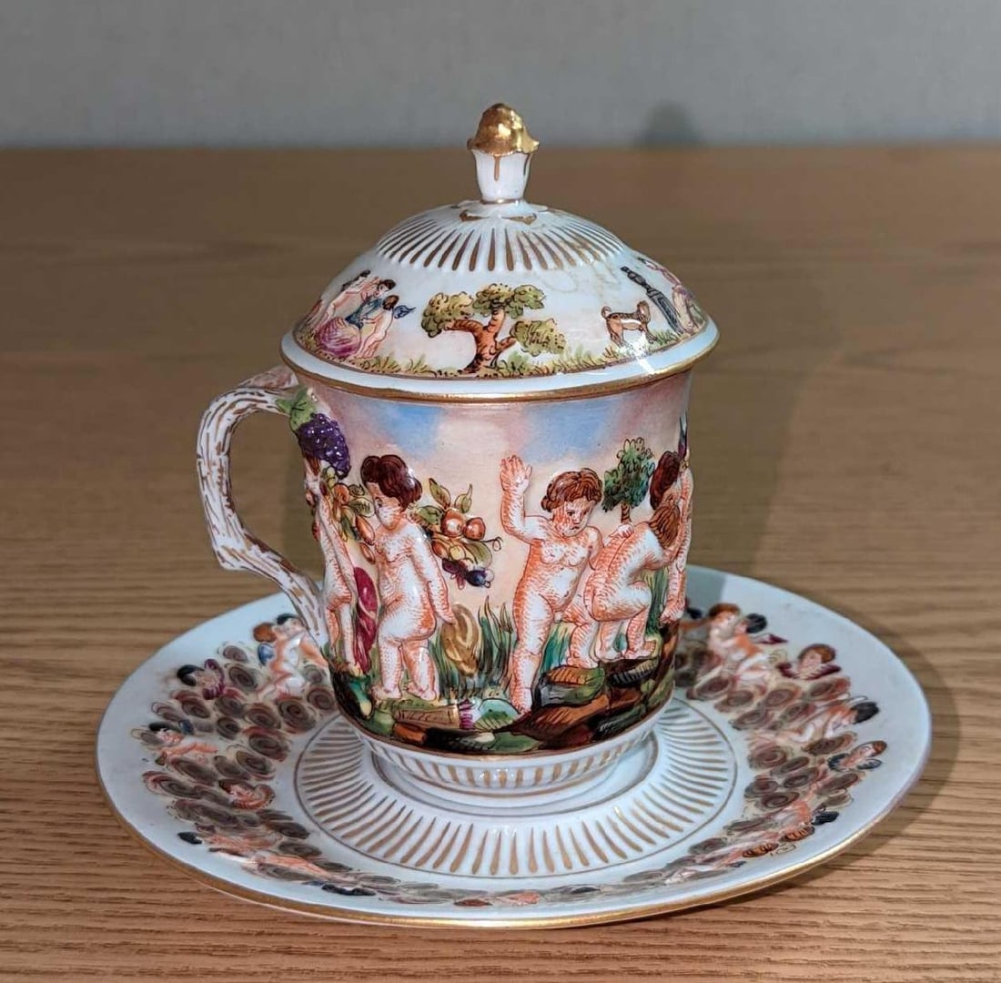 Vintage Capodimonte Italian Cup & Saucer With Lid: Vintage Capodimonte Italian Cup & Saucer With Lid. Made of Made of Hand Painted Capodimonte porcelain. Shows different Cherub in play. This lot includes: (1) Cup. Is 3 1/2" x 3" x 3". 