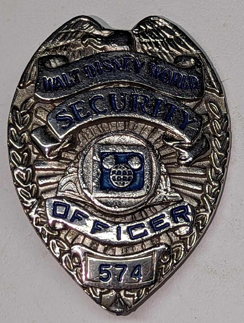 Early 1980s Disney World Female Security Badge 574: Early 1980s Disney World Female Security Badge 5744. Is approx 1 3/4" x 1/4" x 2 3/8" and it weighs under one pound at 0.10lb. The metal badge is in a good, vintage condition with some scr
