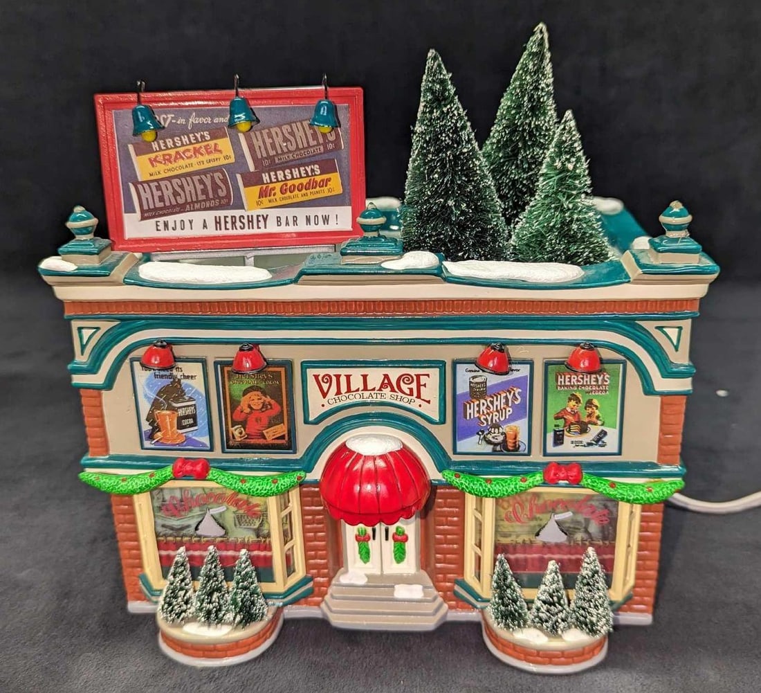 Retired Hershey's Chocolate Shop Original Snow Village: Retired Hershey's Chocolate Shop Original Snow Village. This was originally released from the year 1997 and was retired in the year 2000. Hand-painted ceramic. It comes in its original box that is app