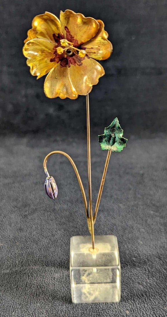 Blooming Metal Flower With Acrylic Base: A blooming flower that is made of what I believe is a light tin or aluminum. Is attached to an acyclic stand. Is approx 2" x 2" x 7 1/2" and it weighs 0.11lb. The base has some sticker res