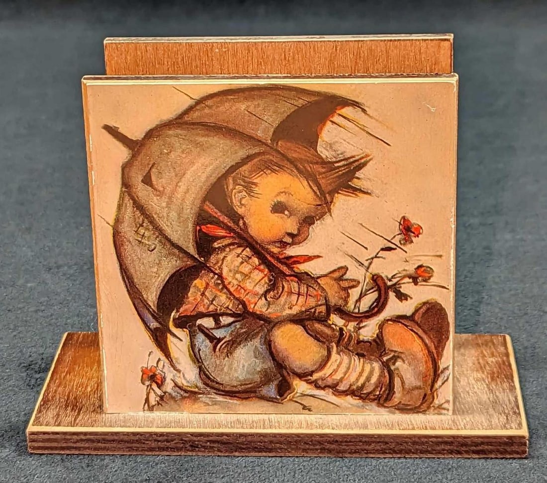 Vintage Hummel Letter Or Napkin Stand: Vintage Hummel Letter Or Napkin Stand. This wood letter or napkin stand shows an young girl with an umbrella on one side, and a young boy with an umbrella on the other. Was made in West Germany. This