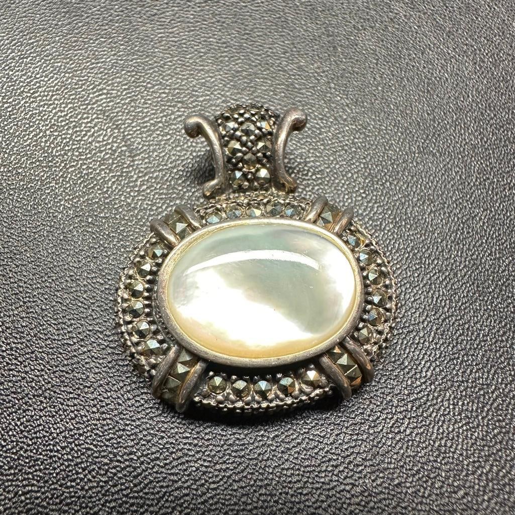 Sterling Silver Marcasite Mother of Pearl Pendant: This piece of jewelry has been tested and researched prior to listing. Please view all our pictures they are part of our description. DETAILS: Metal - Sterling Silver Color - Silver Stones - Mother of