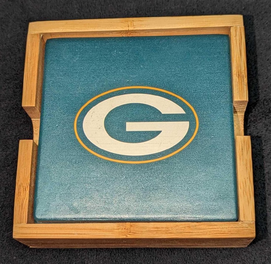 4 Ceramic Green Bay Packers Football Coasters B: 4 Ceramic Green Bay Packers Football Coasters B. Each coaster is approx 3 7/8" x1/4" x 3 7/8". The four coasters and wooden stand are approx 4 1/2" x 4 1/2" x 1 3/4" and it wei