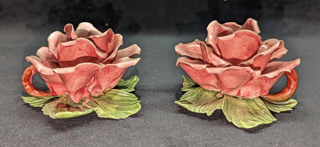 2 Vintage Capodimonte Rose Candleholders: 2 Vintage Capodimonte Rose Candleholders. Each is approx 5" x 5" x3" and the total weight is 1.07lb. The maker and date of creation is unknown. Both have chips on the edges of the petals.