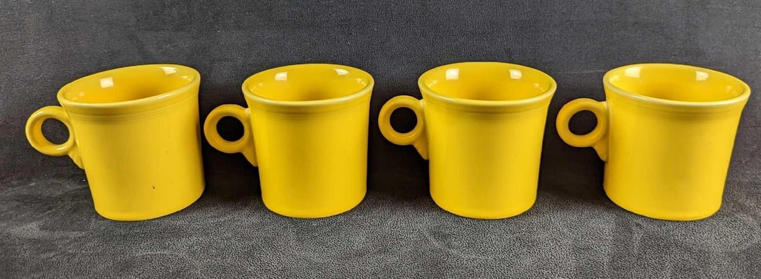 4 Yellow Sunflower HLC Fiesta Mugs: 4 Yellow Sunflower HLC Fiesta Mugs. Each is approx 5" x 2 1/2" x 3 1/2" and together they weigh 3.66lbs. The mugs are in good, used condition with some signs of wear and scratches inside t
