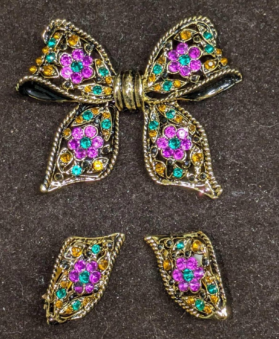 Vintage Gold Tone Bow Brooch & Earrings: Vintage Gold Tone Bow Brooch & Earrings. With colorful glass gems. The brooch is approx 2 3/4" x 3/8" x 2 1/4". Each of the earrings is approx 3/4" x 1/4" x 1/2". The total