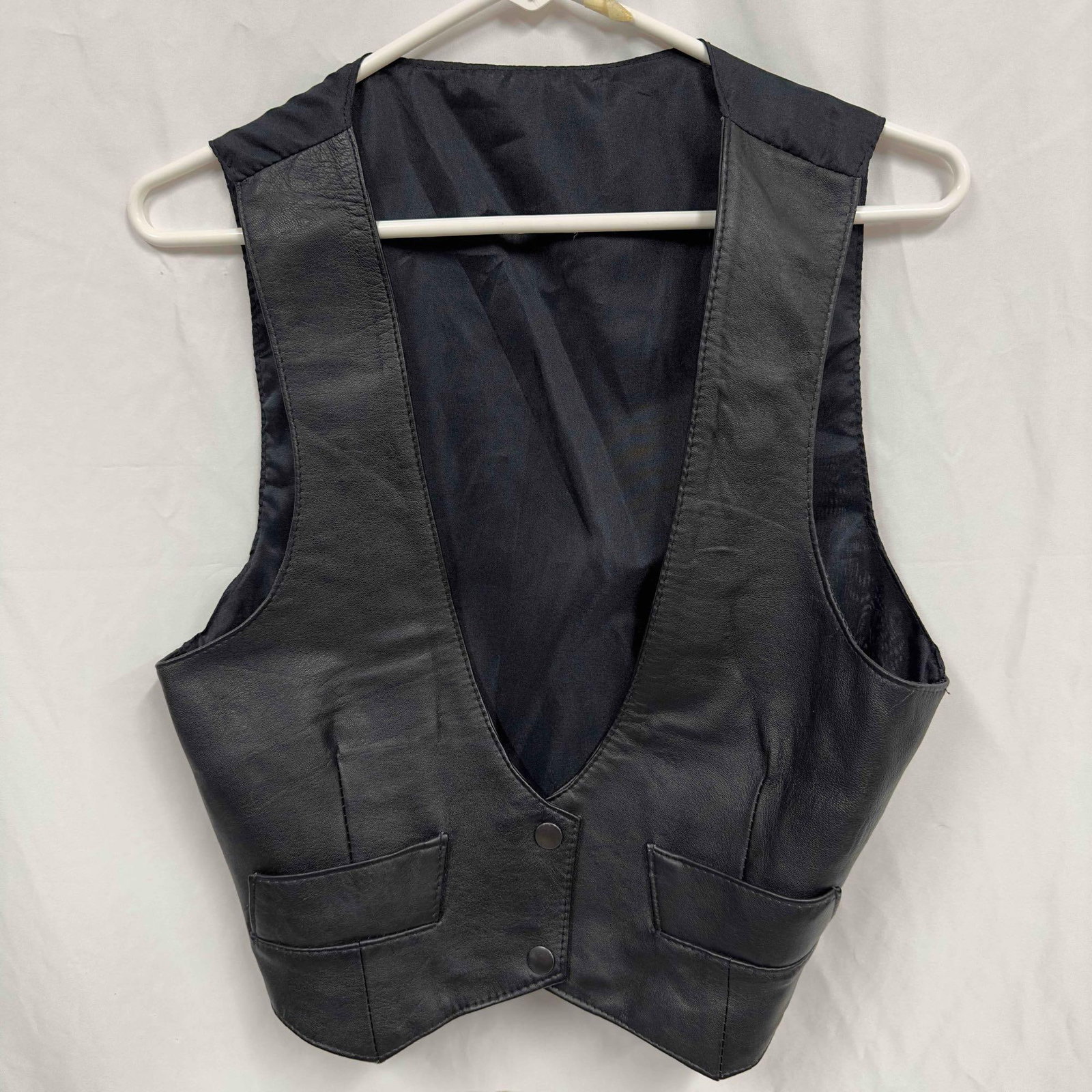 Vera Pelle Genuine Leather Black Vest Small: Vera Pelle Genuine Leather Black Vest Small. This vest has a simple black design with a two button closure on the front. Tag inside the vest reads genuine leather and 100% Polyster made in India. This