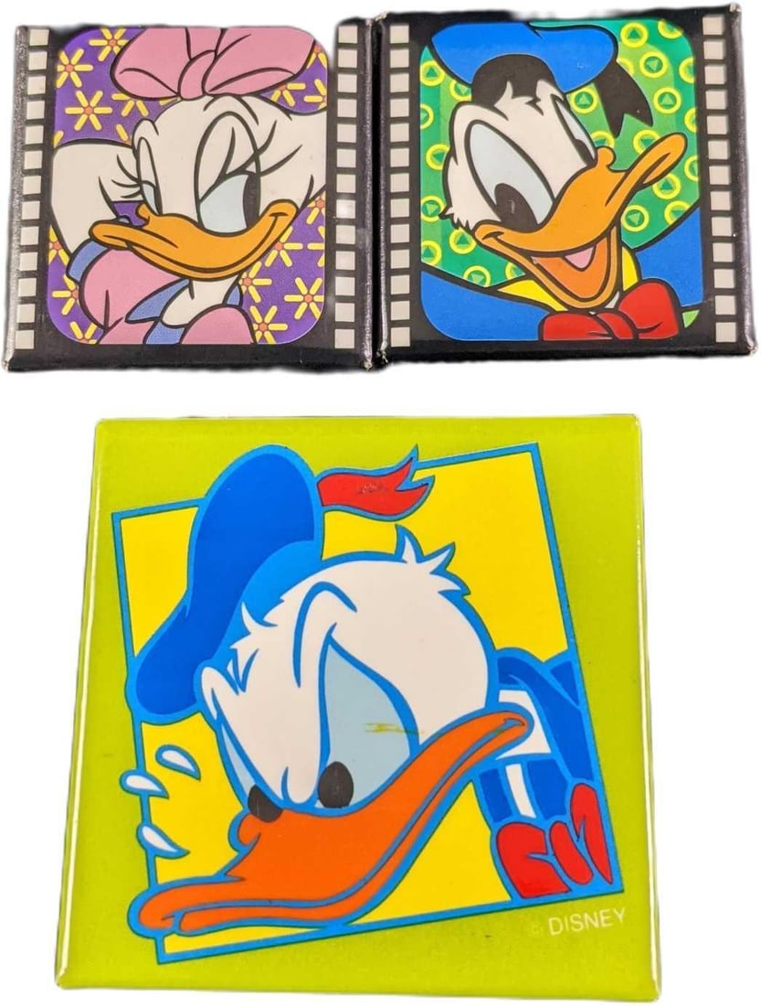 Three Square Donald & Daisy Disney Buttons: This lot includes: (1) Donald Duck "Film" Button. This is approx 1 1/2" x 1 1/2". (1) Daisy Duck "Film" Button. This is approx 1 1/2" x 1 1/2". (1) Angr