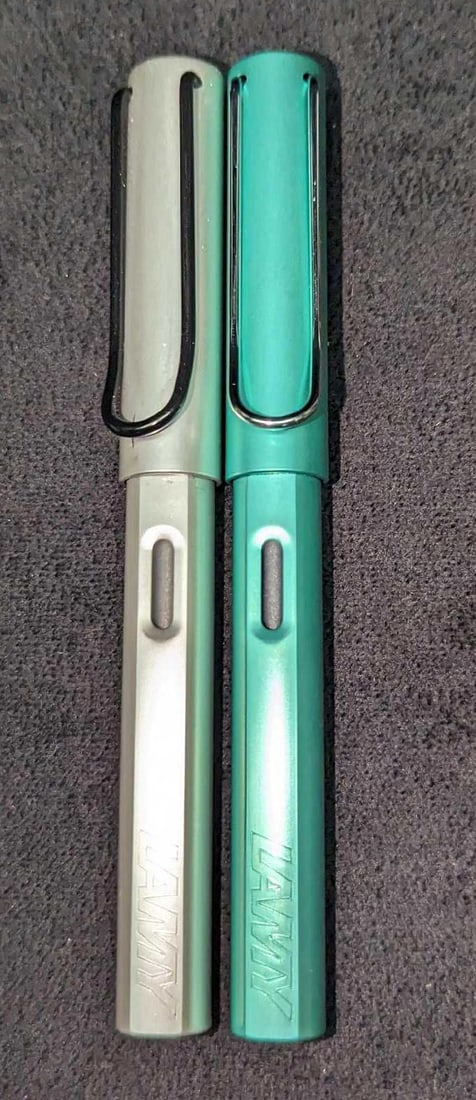 Two Lamy LX Fountain Aluminum Pens: Two Lamy LX Fountain Aluminum Pens. This lot includes two Lamy LX fountain aluminum pens. These have aluminum barrels with black stainless steel nibs. Each pen is approximately 5 1/2" and together