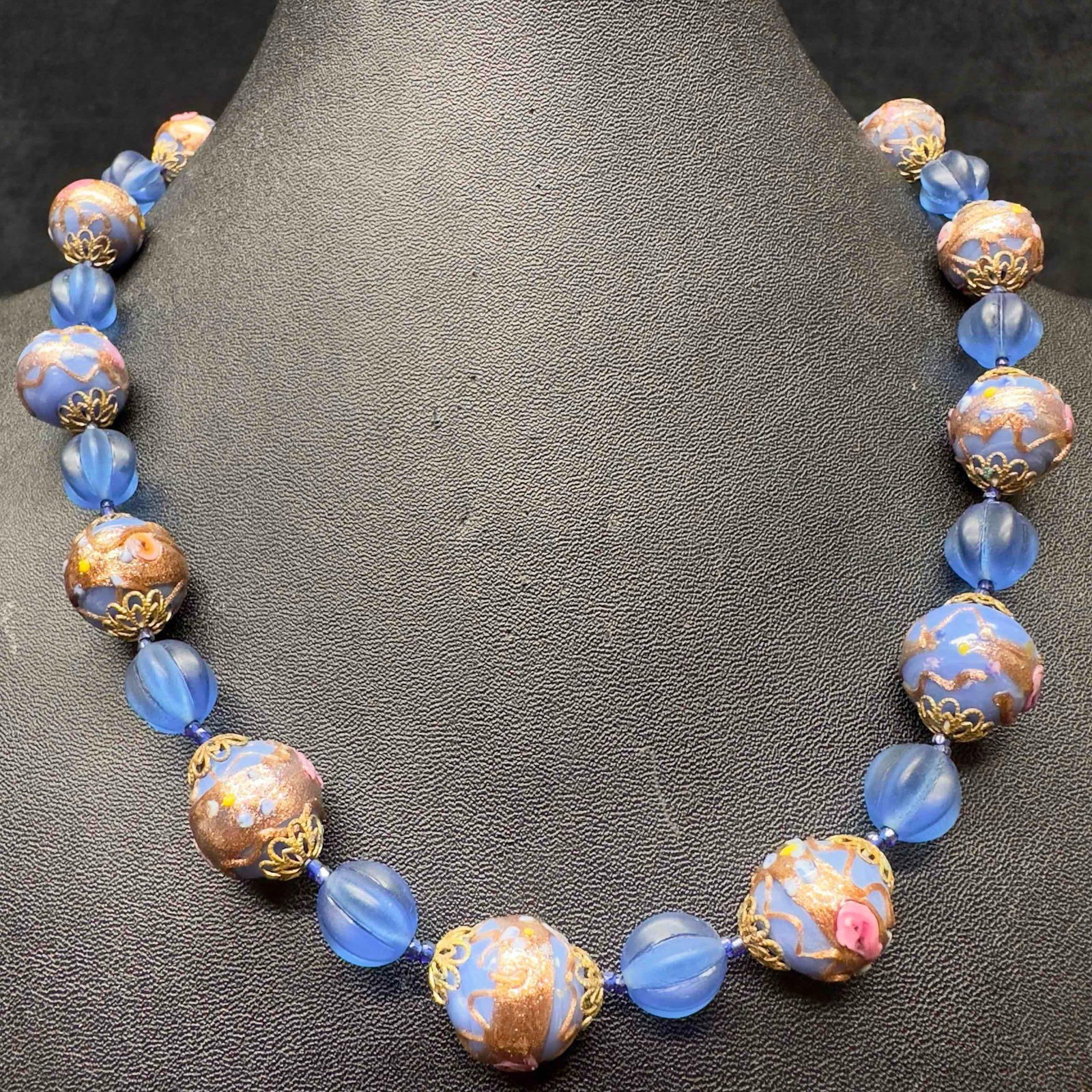 Murano Venetian Art Glass Lamp Work Blue Bead Round Beaded Necklace D78: Murano Venetian Art Glass Lamp Work Blue Bead Round Beaded Necklace D78. Necklace with blue colored glass beads with beautiful designs on each. The necklace features copper colored and floral accents.