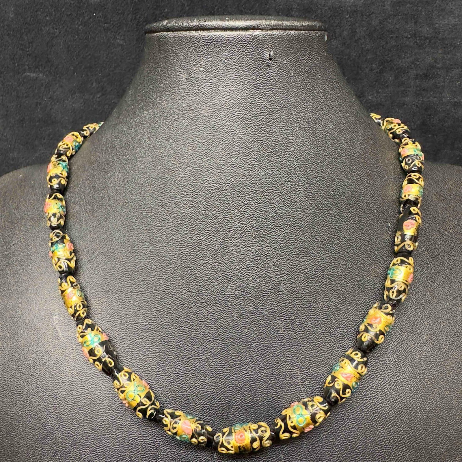 Venetian Murano Glass Lamp Work Oval Black Bead Necklace R: Venetian Murano Glass Lamp Work Oval Black Bead Necklace R. Necklace with black glass oval beads with beautiful hand painted floral designs on each. The necklace features gold colored accents. The nec