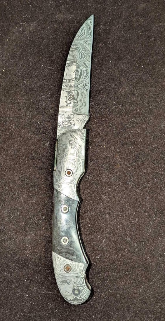 Damascus Steel Fold Up Brown & Black Horn Handle Knife Retired D: Damascus Steel Fold Up Brown & Black Horn Handle Knife Retired D. Here is a fold-up knife made of imported Damascus steel with a brown & black horn handle. These were made in very limited batches by a