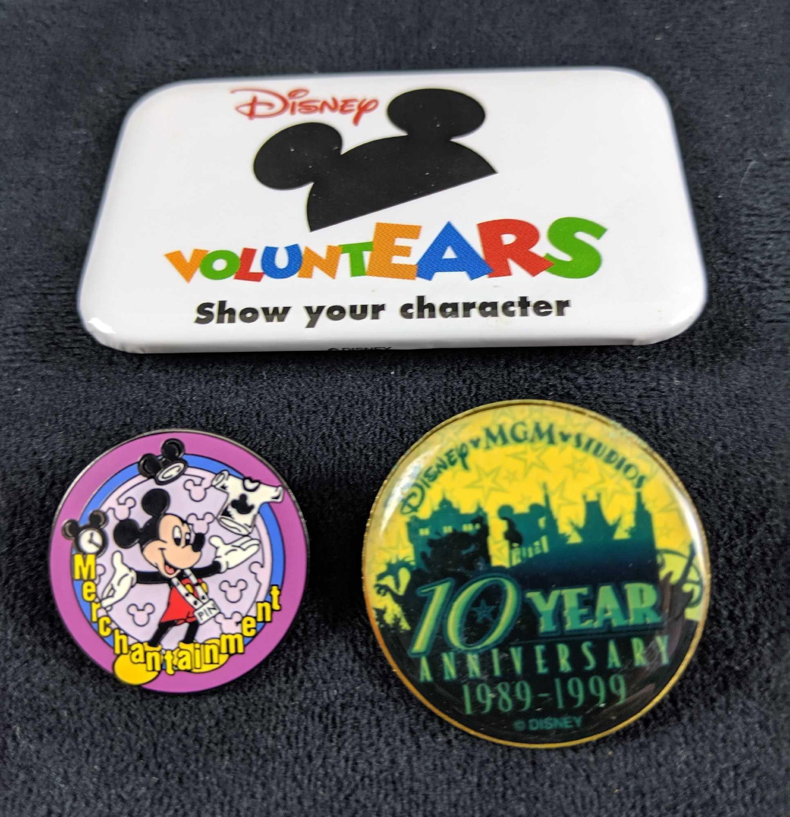 Lot Of Three Disney Cast Member Pins: This lot includes: "Disney Voluntears: Show Your Character" pin that was given to Disney cast members who volunteer on meaningful projects across the globe, with a primary focus on communities where D