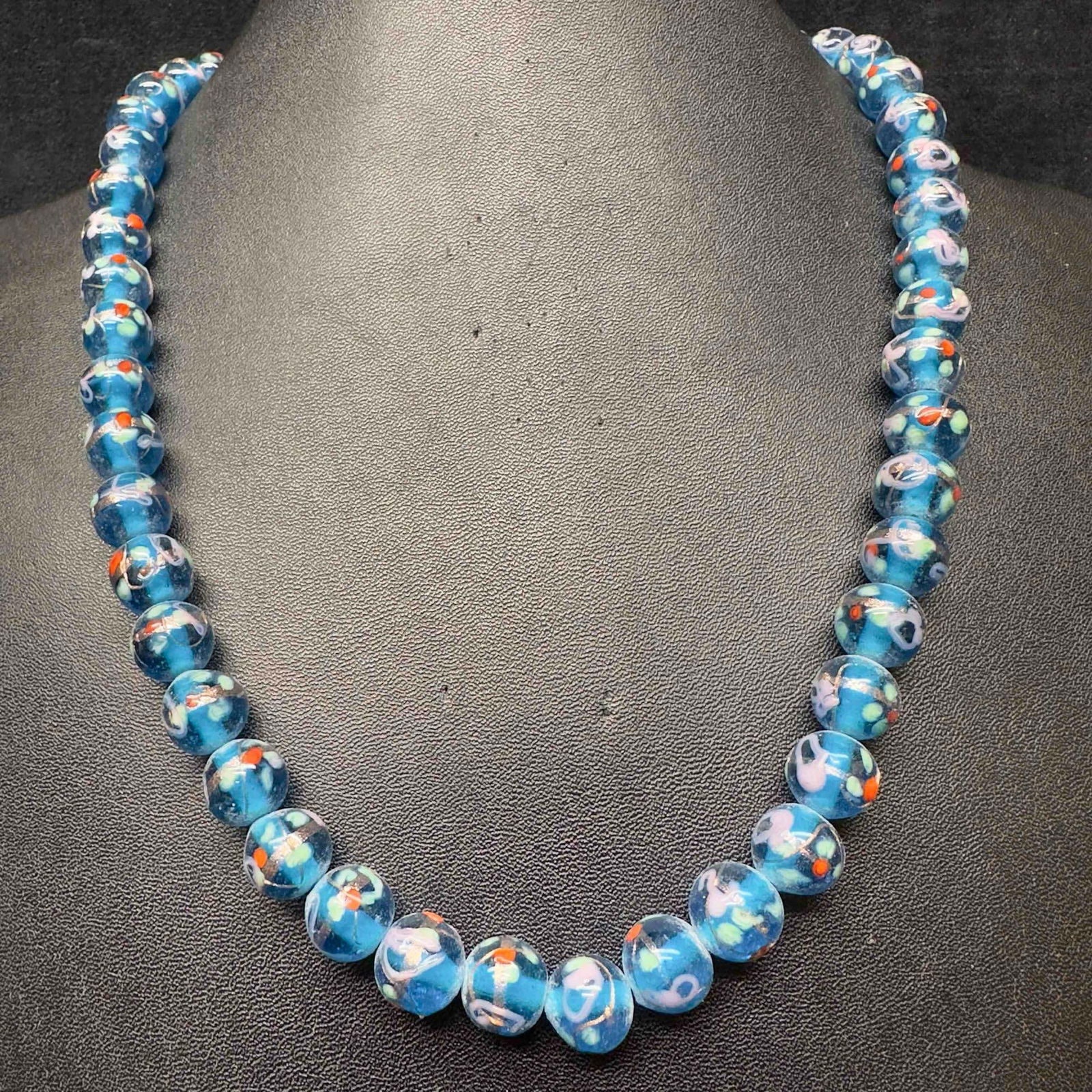 Murano Venetian Lamp Work Glass Art Clear Dark Blue Floral Accents Beaded Necklace E75: Murano Venetian Lamp Work Glass Art Clear Dark Blue Floral Accents Beaded Necklace E75. Necklace with dark blue colored glass beads with a beautiful hand painted design on each. The necklace features