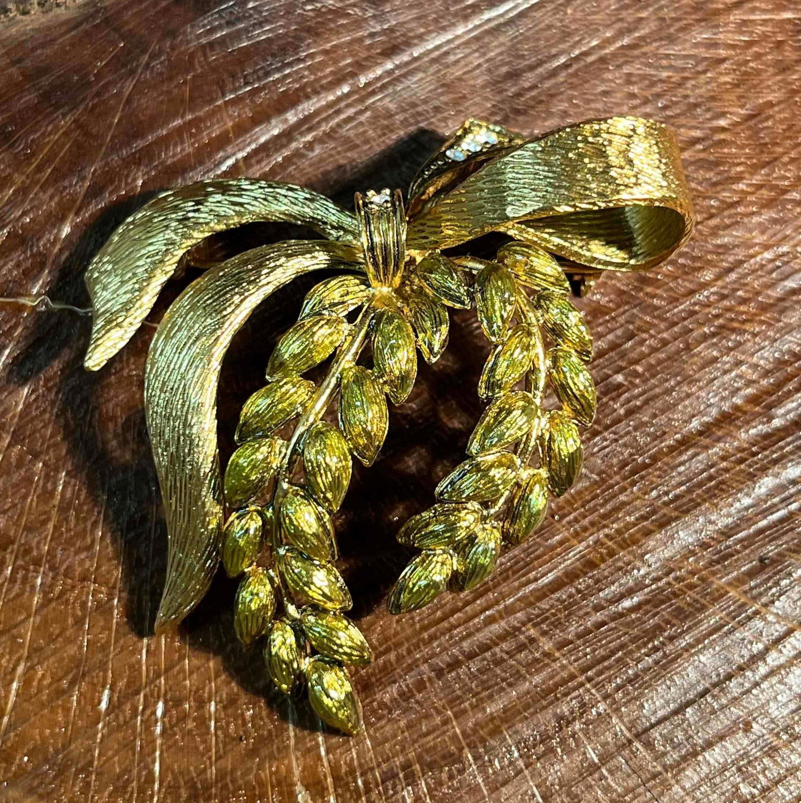 Joan Rivers Brooch Gold Tone Bow Green Enamel Wreath: This lot contains a Joan Rivers Brooch Gold Tone Bow Green Enamel Wreath. It is approx 2 1/4" x 1 3/4" x 3/4". Total weight is approx 0.5oz. Overall the brooch is in good used condition with no notice