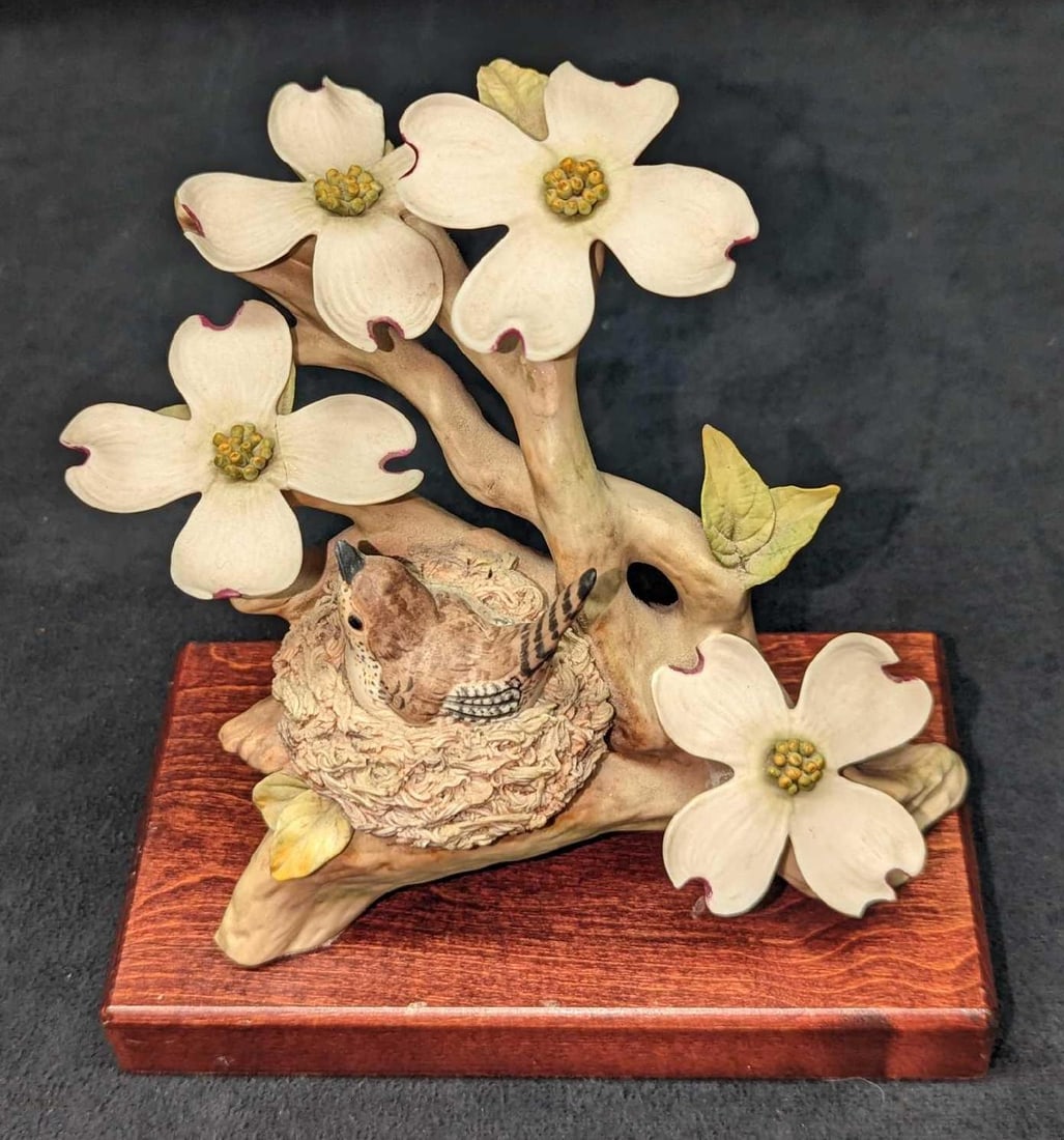 Cybis Birds Wood Wren & Dogwood Tree Branch Figurine: Cybis Birds Wood Wren & Dogwood Tree Branch Figurine. The Porcelain figurine is approx 5 1/2" x 3 1/4" x 5 3/8". The wooden stand is approx 6 1/4" x 3 1/2" x 3/4". One of the flower's petals is b