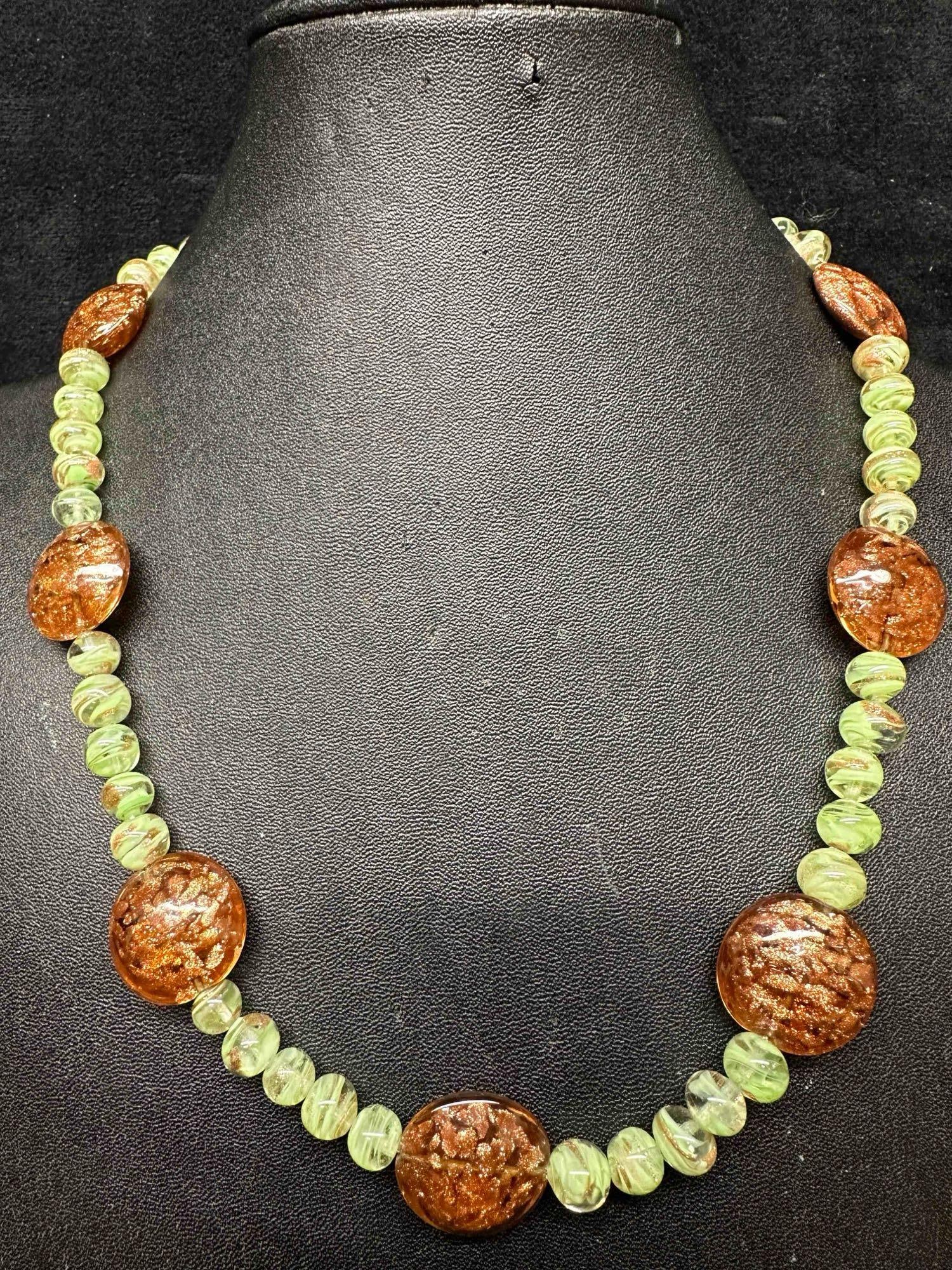 Venetian Murano Art Glass Lamp Work Green Circle Bead Copper Accents Beaded Necklace D4: Venetian Murano Art Glass Lamp Work Green Circle Bead Copper Accents Beaded Necklace D4. Necklace with green glass beads with beautiful designs on each. The necklace features copper accents. The neckl