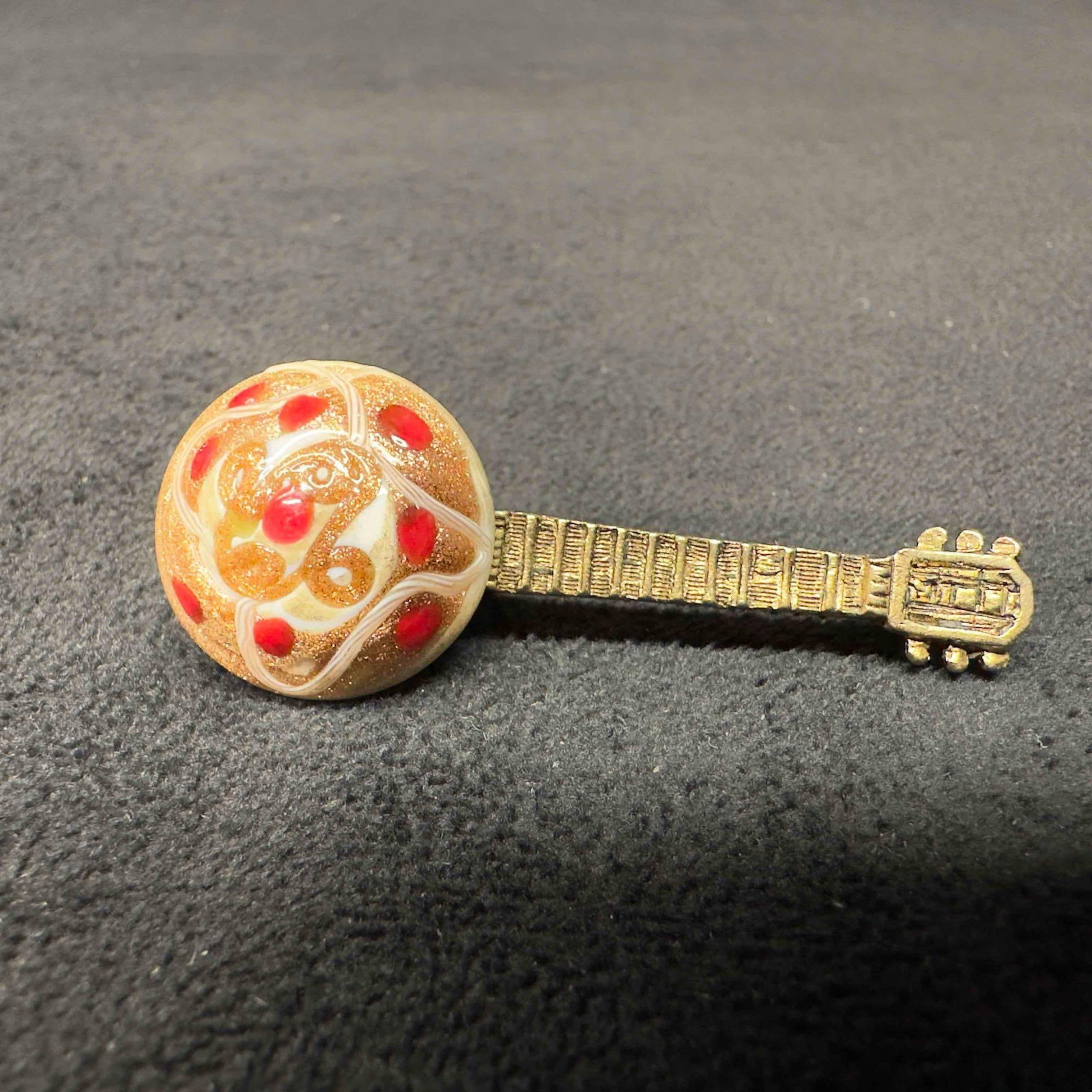 Murano Venetian Lamp Work Glass Art White Floral Guitar Lapel Pin: Murano Venetian Lamp Work Glass Art White Floral Guitar Lapel Pin. Lapel pin with a white colored glass bead with a beautiful hand painted design. The lapel pin features red rose colored accents. This
