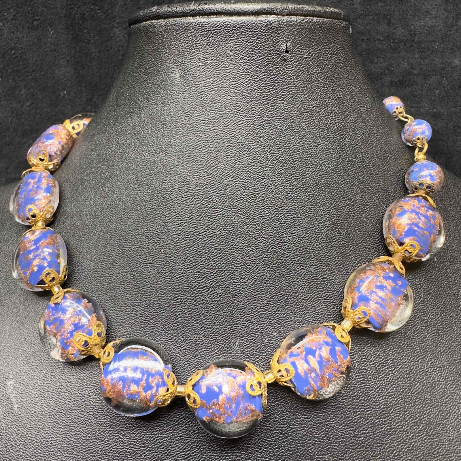 Venetian Murano Lamp Work Glass Dark Blue Round Bead Copper Accent Beaded Necklace A39: Venetian Murano Lamp Work Glass Dark Blue Bead Copper Accent Beaded Necklace A39. Necklace with dark blue colored glass beads with beautiful designs on each. The necklace features copper colored accen