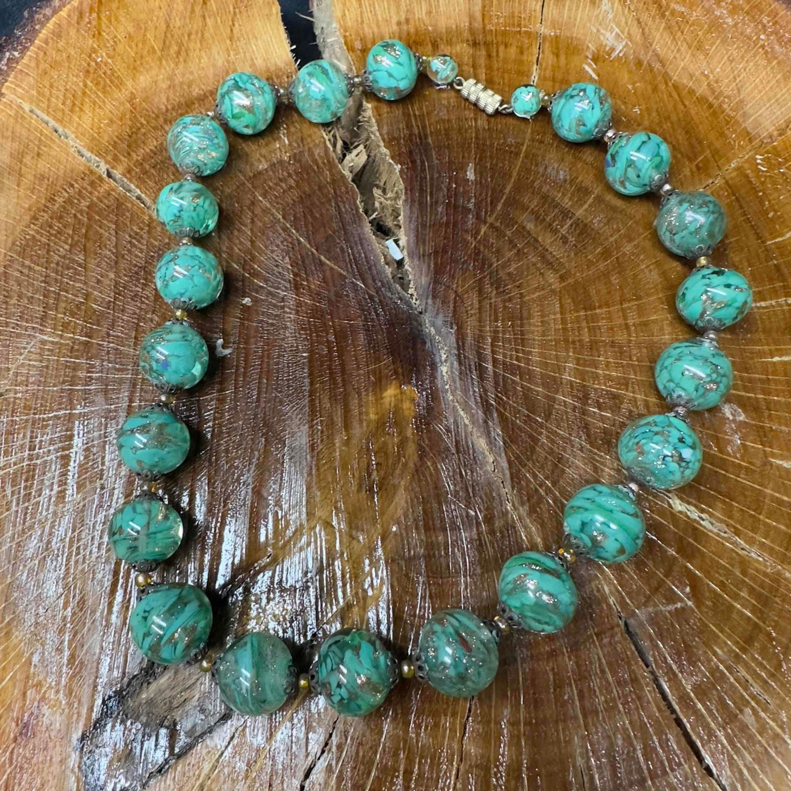 Venetian Murano Lamp Work Glass Green Round Bead Copper Accent Beaded Necklace A38: Venetian Murano Lamp Work Green Round Bead Copper Accent Beaded Necklace A38. Necklace with green colored glass beads with beautiful designs on each. The necklace features copper colored accents. The