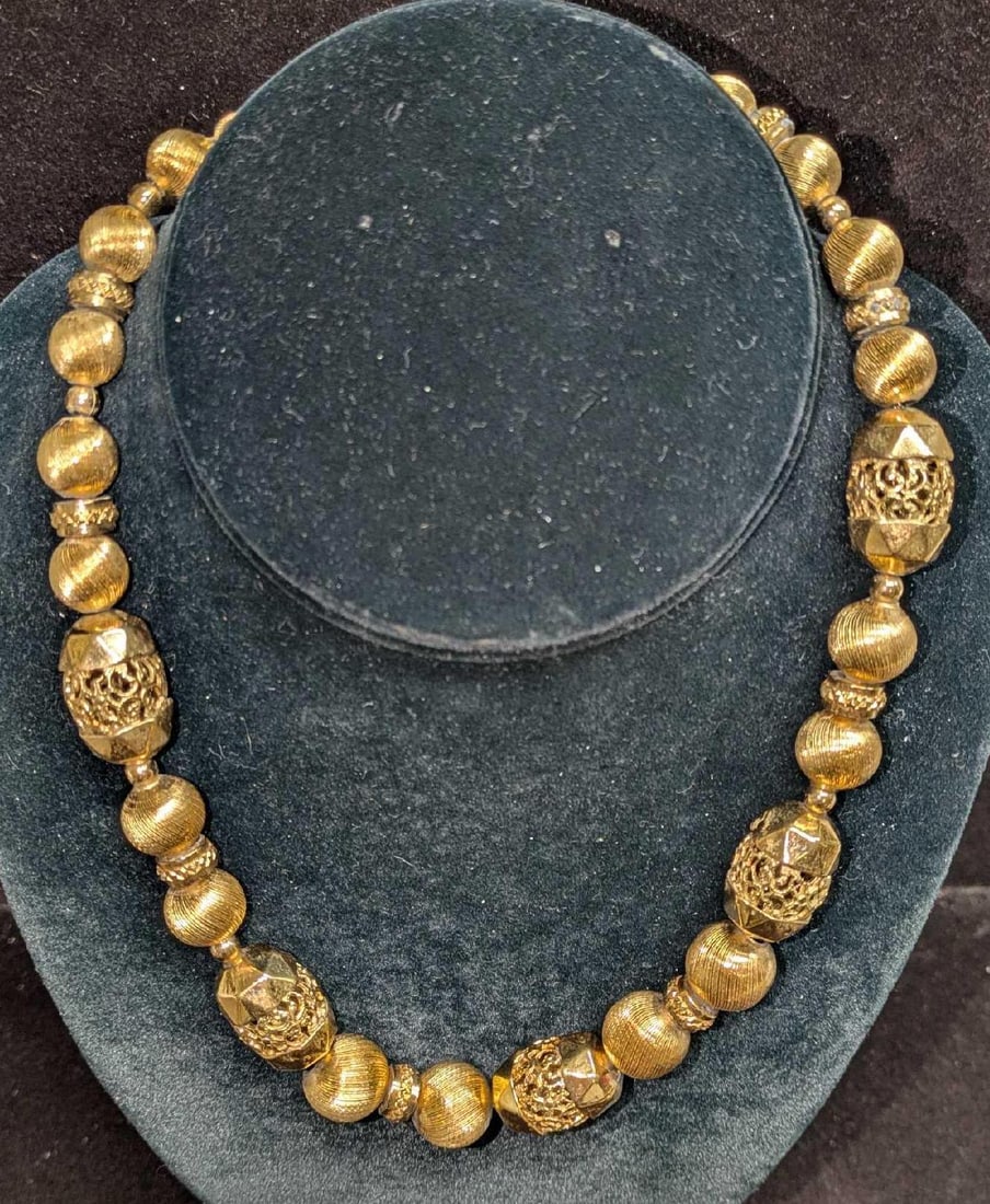 Vintage Monet Gold Tone Beaded Necklace: Vintage Monet Gold Tone Beaded Necklace. Has textured beads, filigree ends and shining polished rounds. This also has a Monet tag near the clasp. This is approx 18" and it weighs 0.14lb. Has some ligh