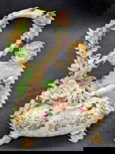 Ucagco Cherub On Basket Figurine: This hand-painted porcelain figurine. The vine loop has birds and flowers. A cute little piece to accent any shelf. Marked N with a C over it on the bottom. Made by Ucagco in Japan, the exact date is