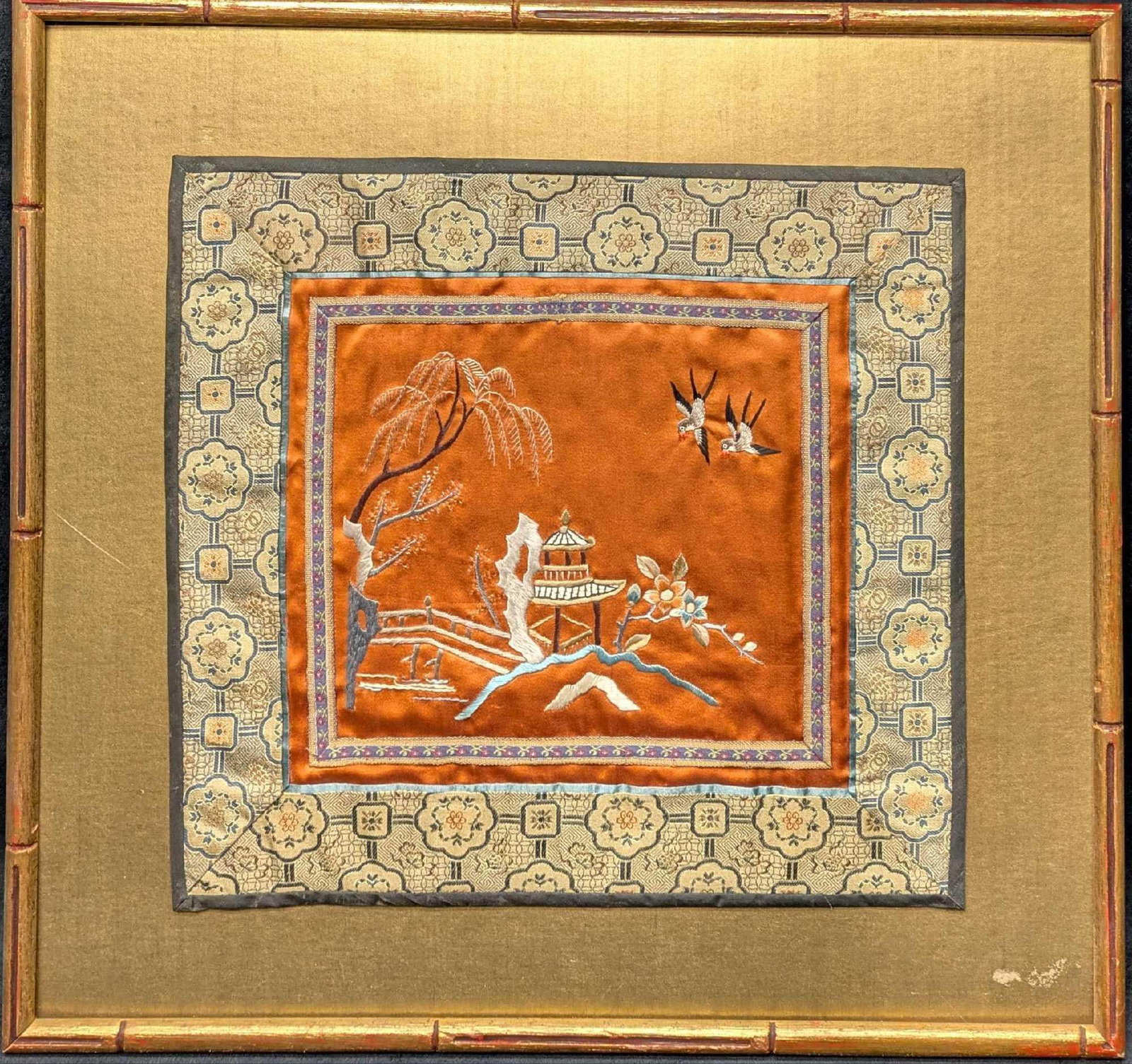 Vintage Silk Embroidery Art Asian Style Embroidery: Vintage Silk Embroidery Art Asian Style Embroidery This beautiful piece is an Asian silk embroidery of a small landscape and swallows on an orange background and intricate border. This piece is framed