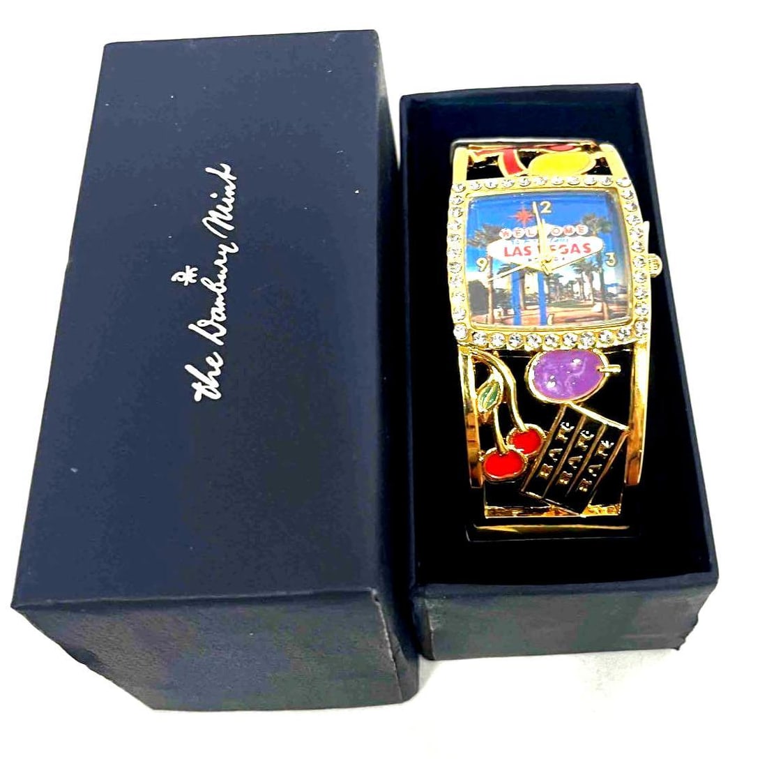 The Danbury Mint Las Vegas Watch In Box: This lot contains a The Danbury Mint Las Vegas Watch In Box. The box is approx 3 3/4" x 1 3/4" x 3 1/4" and it weighs about 0.1lbs. Overall the Watch is in good used condition as it does not appe