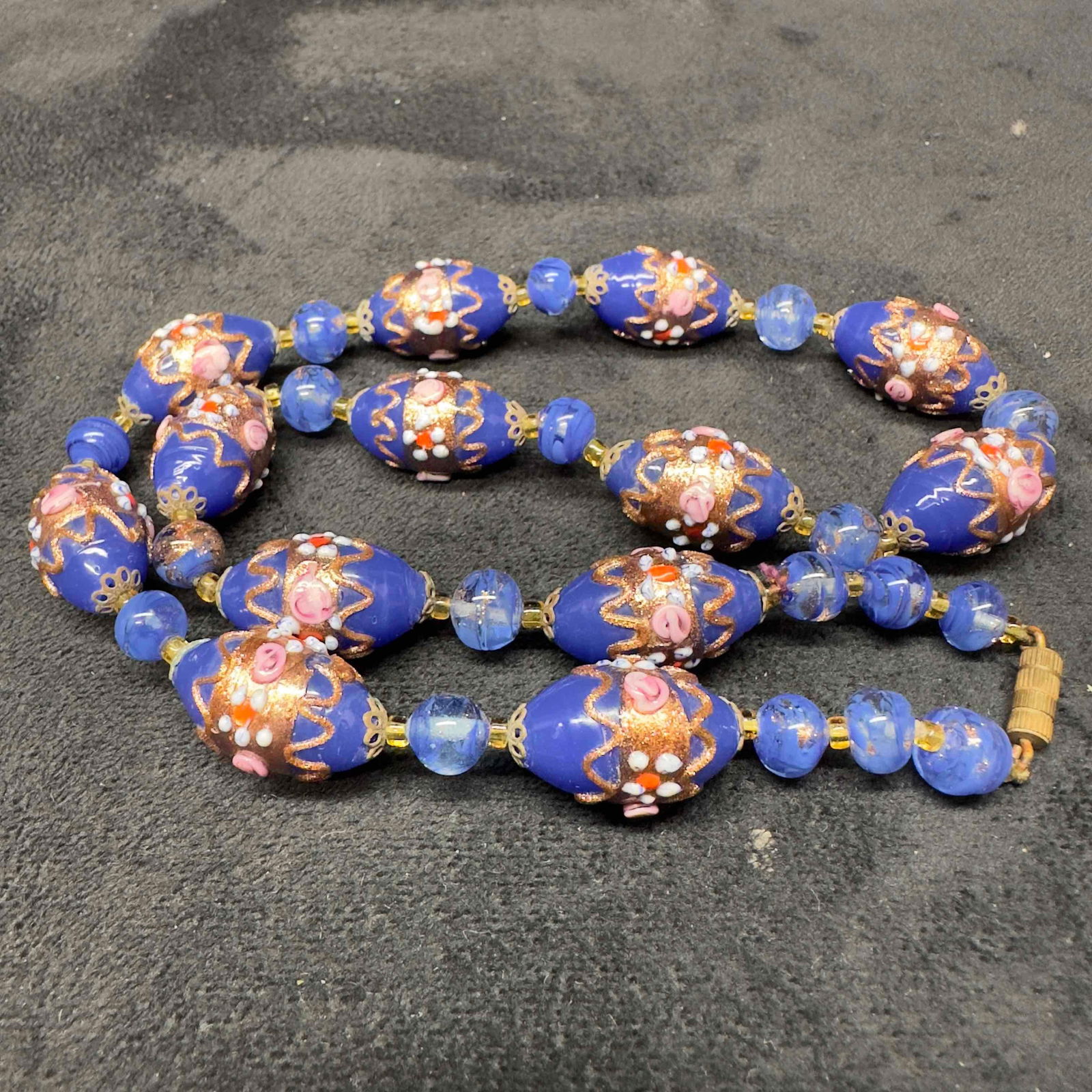 Venetian Murano Glass Lamp Work Dark Blue Fiorato Round Beaded Necklace B3: Venetian Murano Glass Lamp Work Dark Blue Fiorato Round Beaded Necklace B3. Necklace with dark blue glass beads with beautiful floral designs on each. The necklace features copper colored accents. The