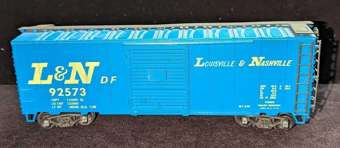 Atlas O-Gauge Louisville & Nashville Box Car: Atlas O-Gauge Louisville & Nashville Box Car. This is approximately 11" x 3" x 3 1/2" and it weighs 0.56lb. The box car has some markings and a ladder on the side is slightly loose.