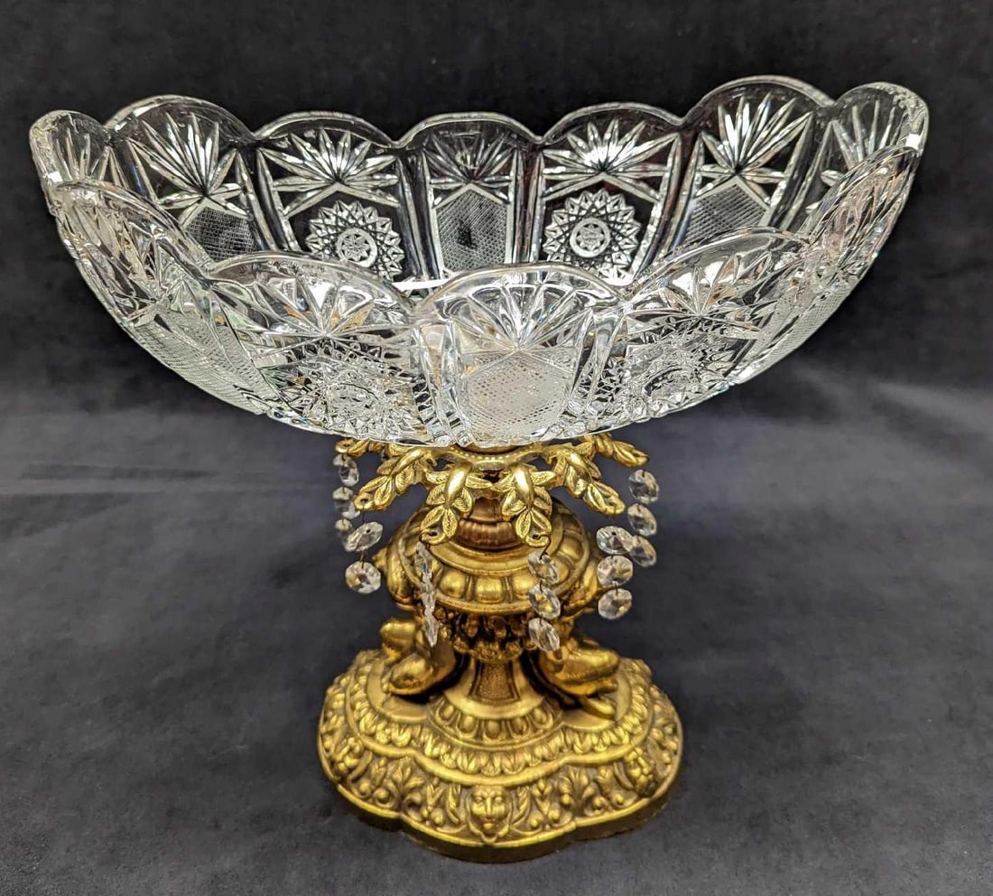Vintage Oval Glass Bowl On Gold Metal Base (F64): Vintage Oval Glass Bowl On Gold Metal Base (F64). The maker and date of creation are unknown. Gold-tone base has lots of details from the cherubs to face patterns. Is missing two sets of the dangling 