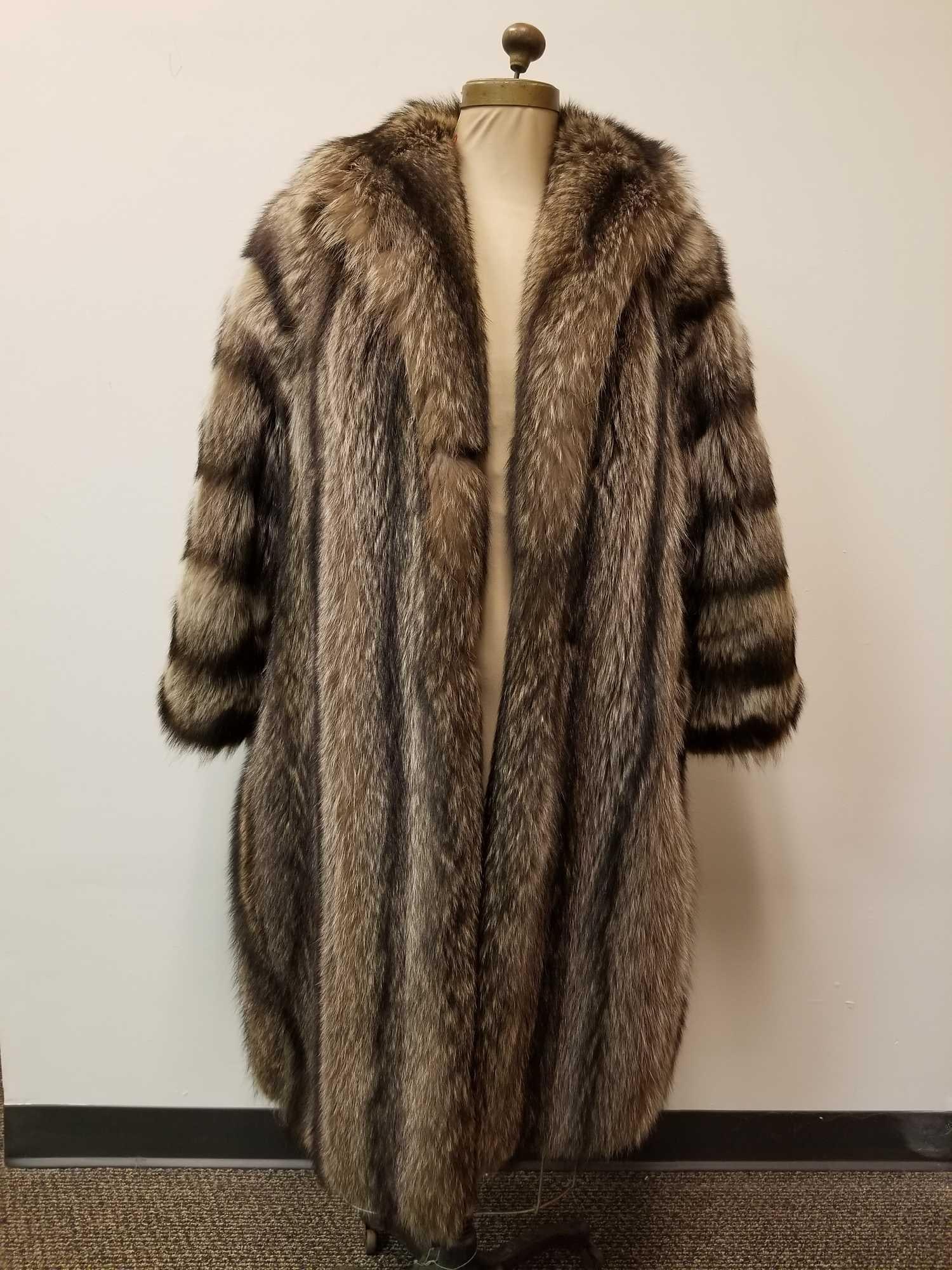 Full Length Raccoon Fur Coat: This full length raccoon fur coat is by an unknown manufacturer and is in great used condition with no known damages. This coat features dark brown linen interior, 2 outside concealed pockets, as well