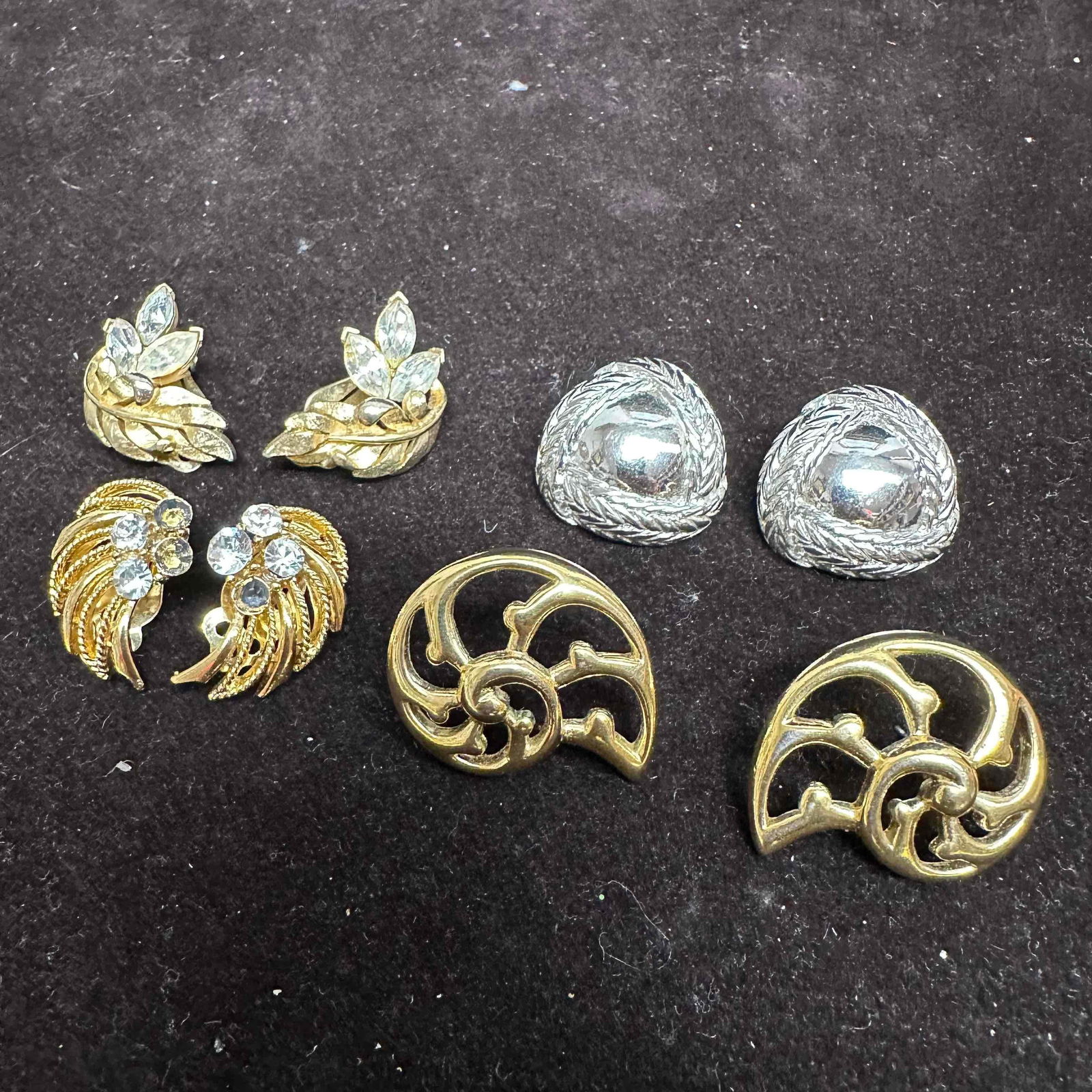 Trifari and Lisner Designer Costume Jewelry Earrings Lot 4 Pairs: Collection of four pairs of vintage designer costume earrings including Trifari and Lisner. Features gold and silver tone finishes with rhinestone accents and textured designs. Includes abstract, leaf