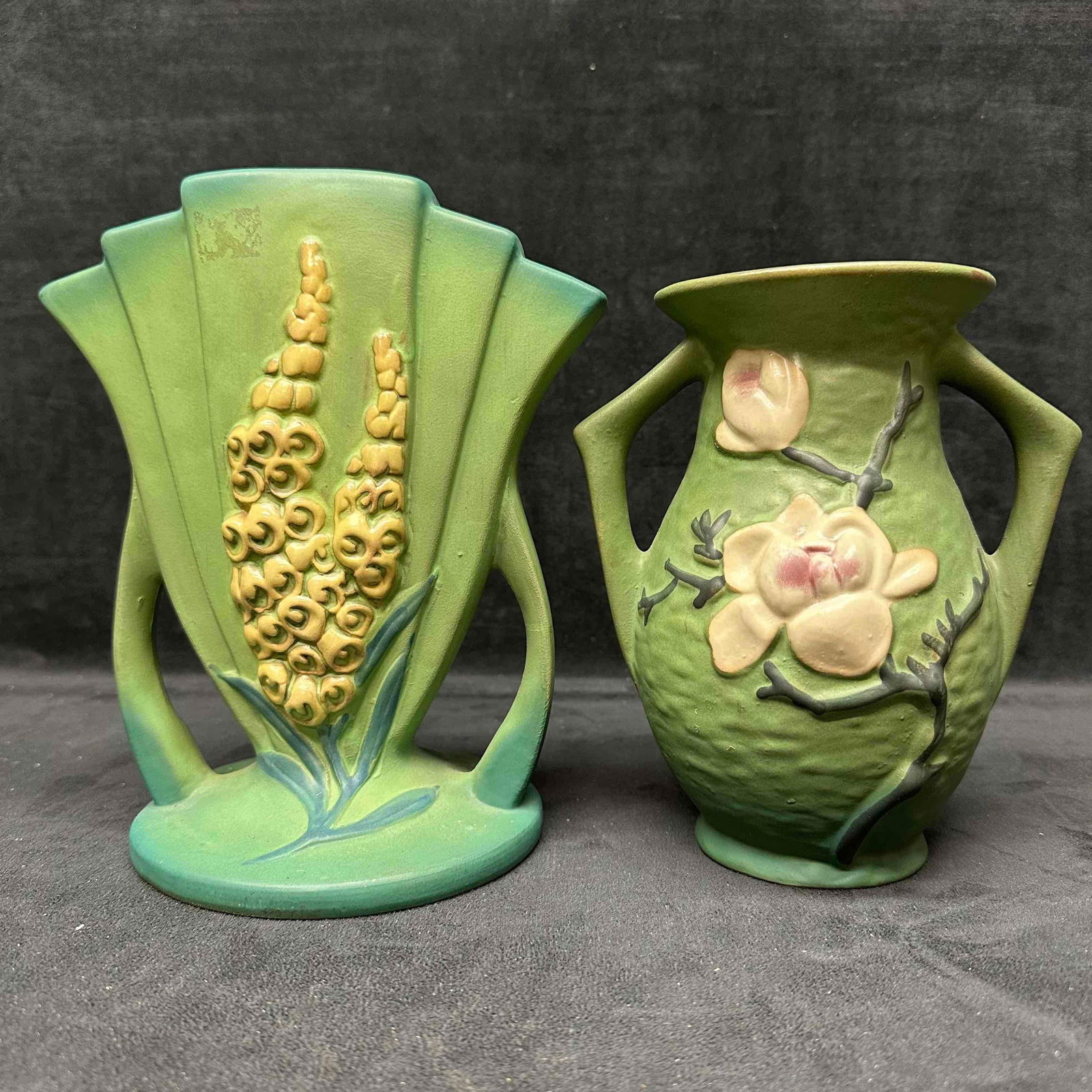 Pair of Roseville Pottery Vases Foxglove Fan Vase #117-8 & Magnolia Double-Handled Vase #90-7: Offered here is a pair of authentic vintage Roseville art pottery vases, both in a soft green matte glaze with raised floral decoration. • Foxglove Fan Vase (#117-8): Features a fan-shaped body
