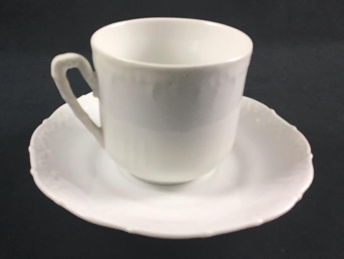 White Porcelain Tea Cup and Saucer: This lot consists of one tea cup and one matching saucer. They are white and have an embossed design on the rims of both cup and saucer. The embossed design gives the set a nice texture. They are