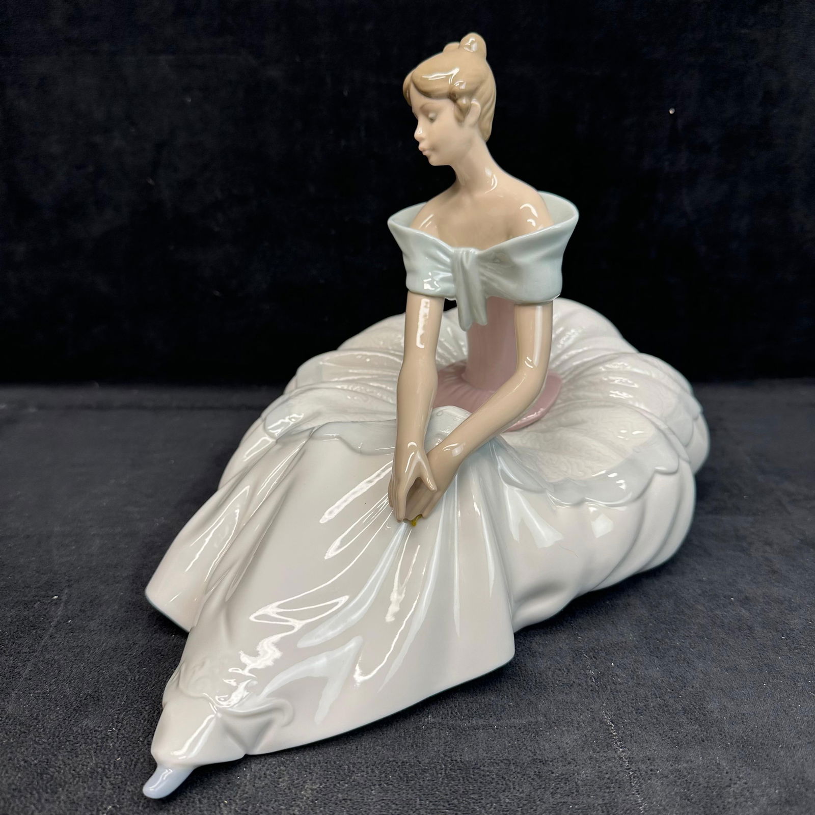 NAO by Lladro Porcelain Figurine Hope Ballerina No. 1266: Elegant style NAO by Lladro porcelain figurine depicting a young woman ballerina seated gracefully in a flowing white gown with pale pink bodice and soft blue shawl. Glazed finish with detailed folds