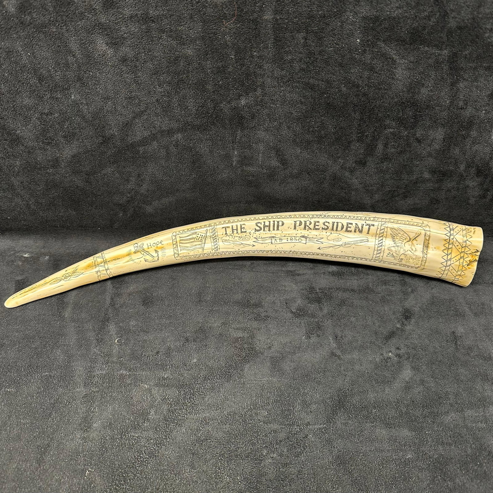 Faux Scrimshaw Replica Walrus Tusk The Ship President AD 1850 Resin Reproduction: Detailed resin scrimshaw replica tusk featuring se/nautical scenes and engraved text reading “The Ship President AD 1850.” The piece is decorated with etched imagery of sailing ships, eagles, 