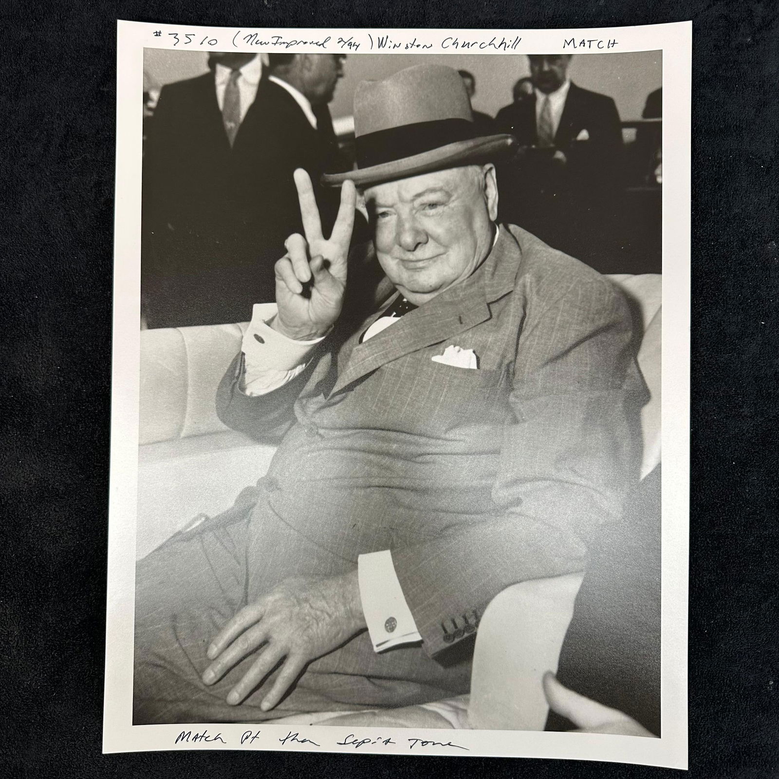 Vintage Silver Gelatin Print of Winston Churchill V for Victory Pose Black and White: Vintage analog black-and-white photo print depicting Winston Churchill giving his iconic “V for Victory” hand gesture. Churchill is shown seated in a suit and hat, exuding his characteristic d