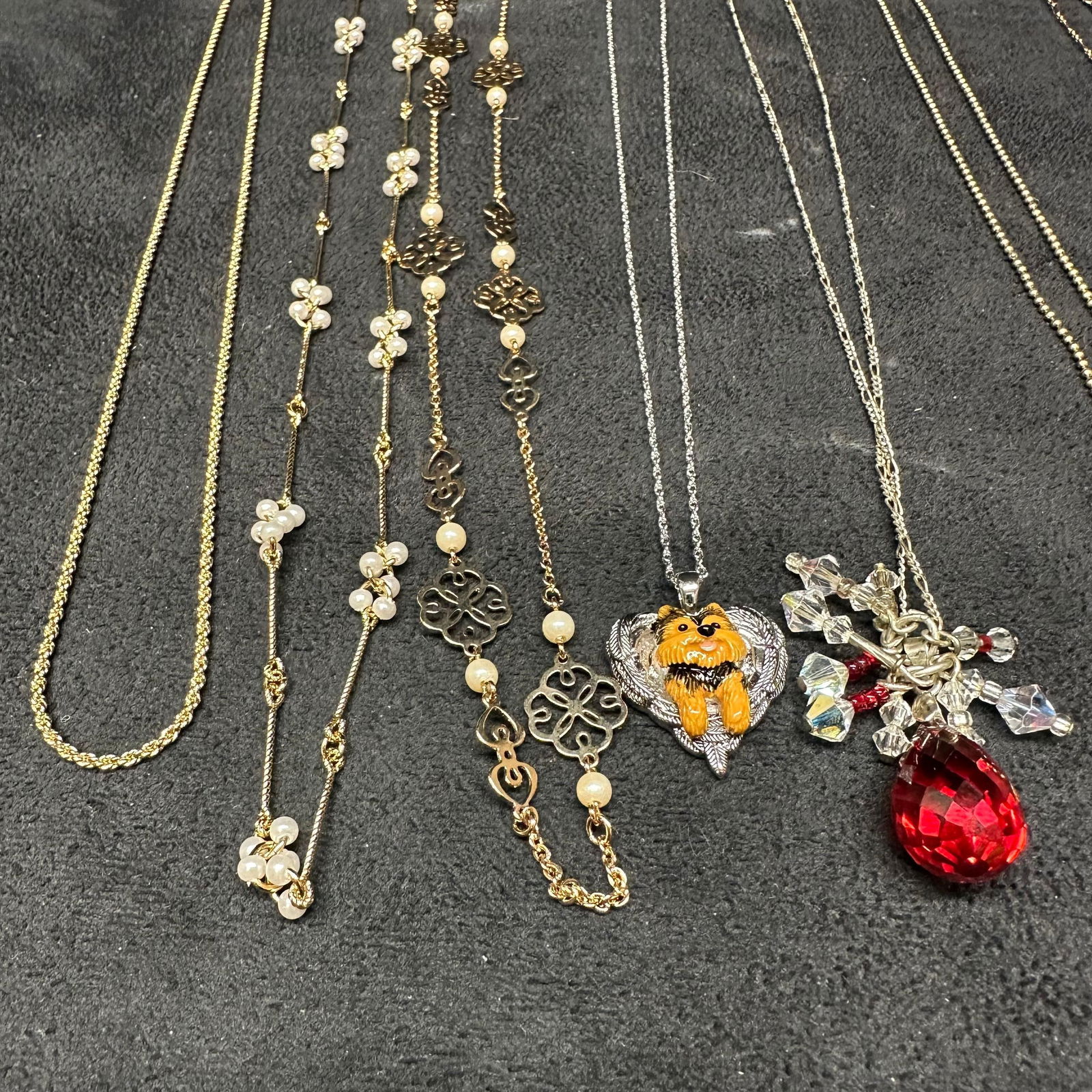 Modern and Vintage Costume Jewelry Necklaces M72: Assorted lot of vintage and modern costume jewelry and necklaces featuring a mix of gold-tone and silver-tone chains with various pendants and charms, including a Pomeranian dog heart pendant, red cry