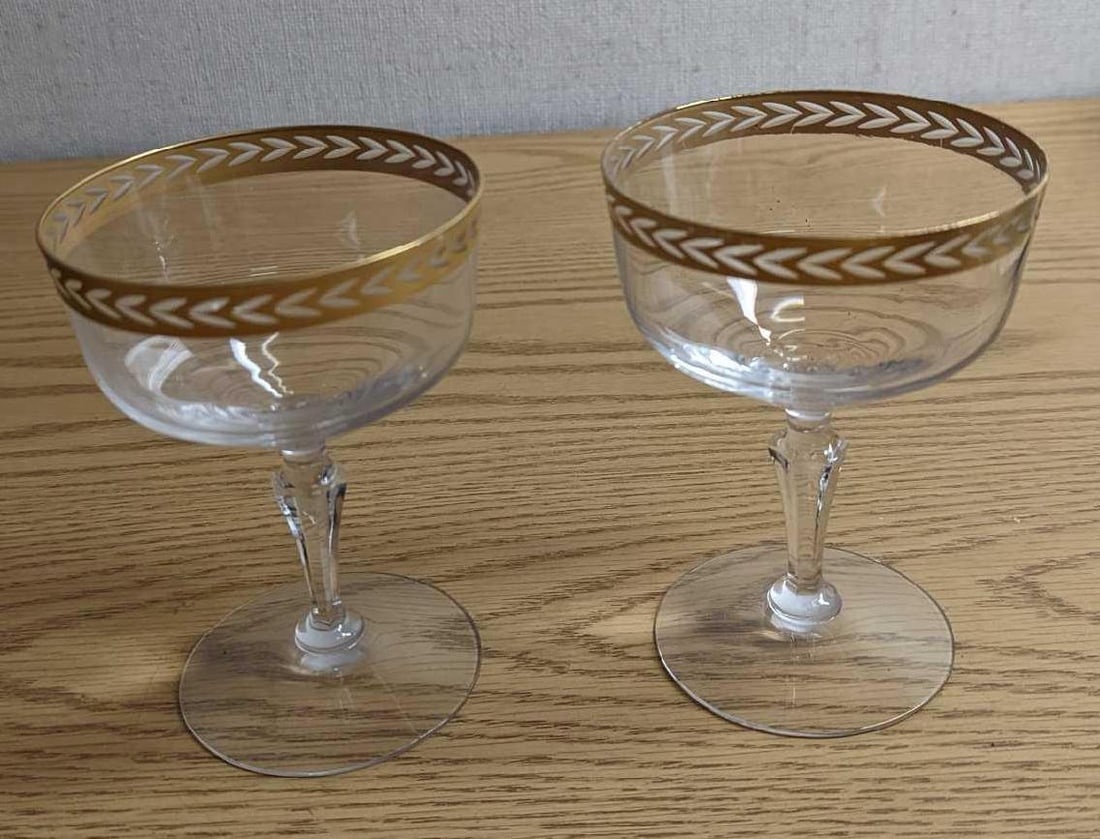 2 Vintage Fostoria Olympic Gold Trim Champagne Glasses: 2 Vintage Fostoria Olympic Gold Trim Champagne Glasses. Each glass is approx 3 3/4" x 3 3/4" x 5 1/4" and together they weigh 0.74lb. The glasses are in a good, vintage condition with some wear on the