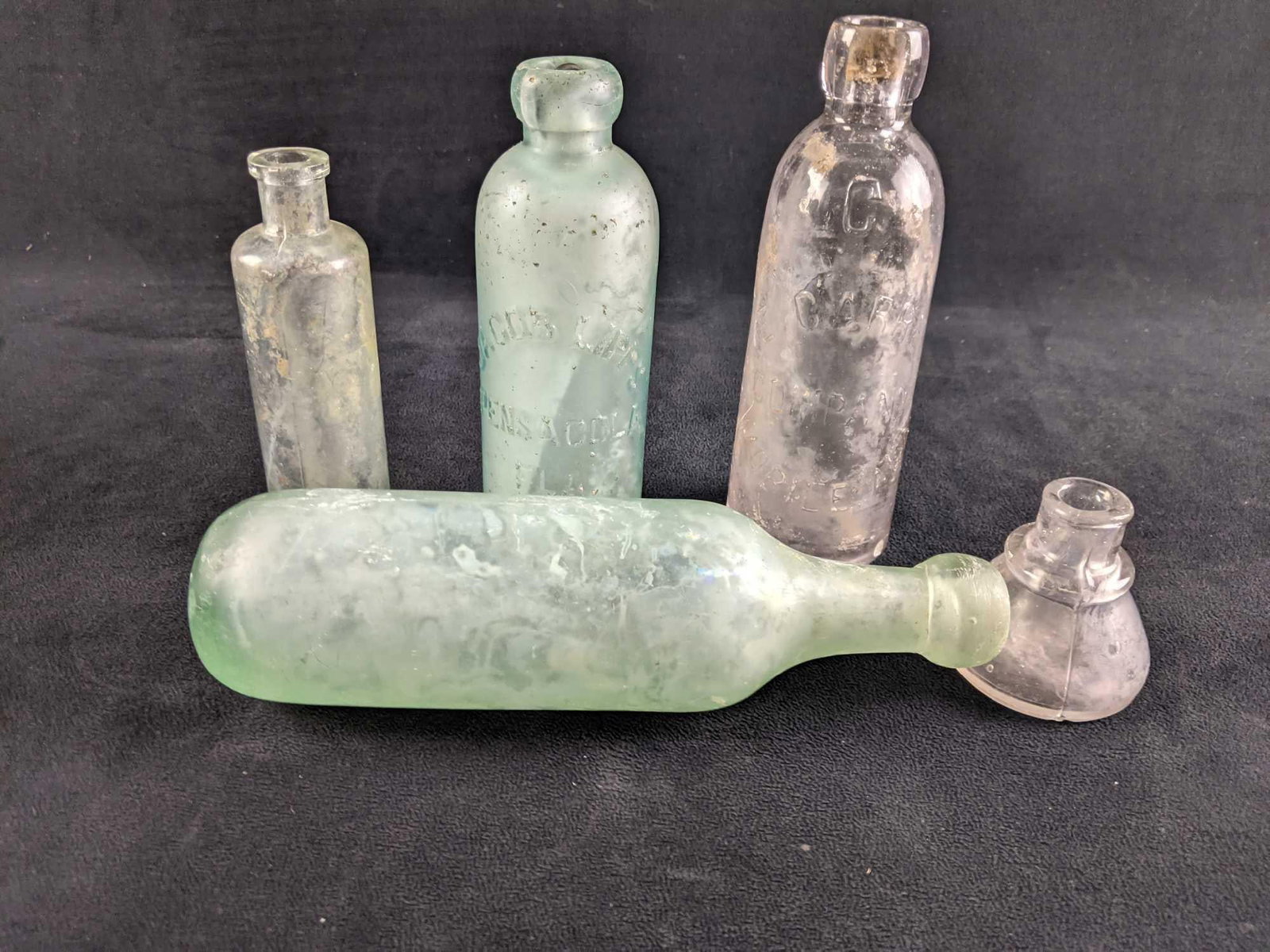 Five Antique Glass Bottles: Five Antique Glass Bottles This lot has five antique glass bottles These bottles are in antique condition with some fogged glass and a few chips. One bottle was designed to lay on its side. These are 