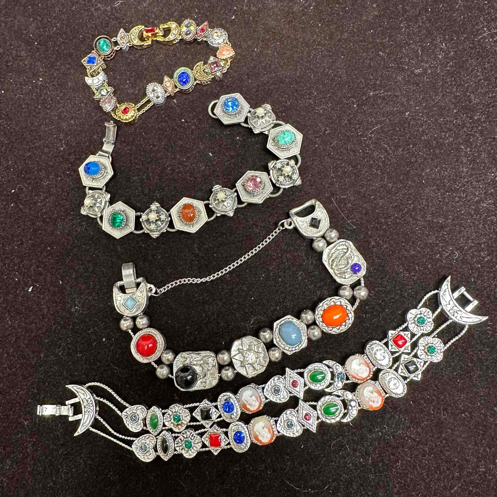 Vintage Victorian Revival Style Stone Cameo Charm Bracelets Set of Four: Silver and gold toned bracelet set. These bracelets feature multiple rhinestones, stones, enamel, cameo, and faux stone charms. These items are in good pre-owned, previously displayed condition with l