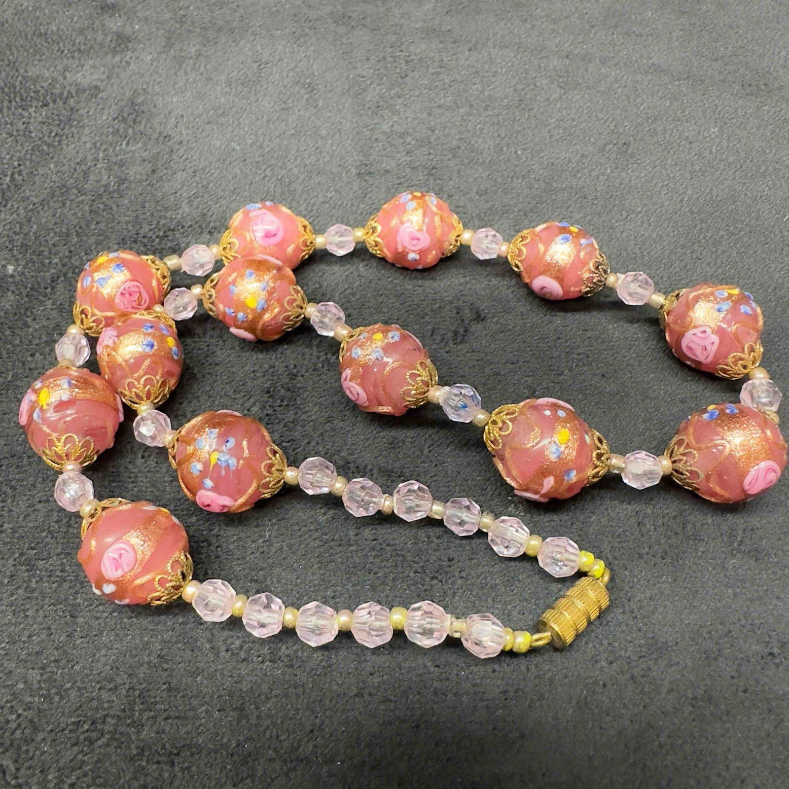 Venetian Murano Lamp Work Glass Pink Round Bead Fiorato Floral Beaded Necklace A91: Venetian Murano Lamp Work Glass Pink Round Bead Fiorato Floral Beaded Necklace A91. Necklace with pink glass beads with beautiful designs on each. The necklace features copper accents. The necklace fe