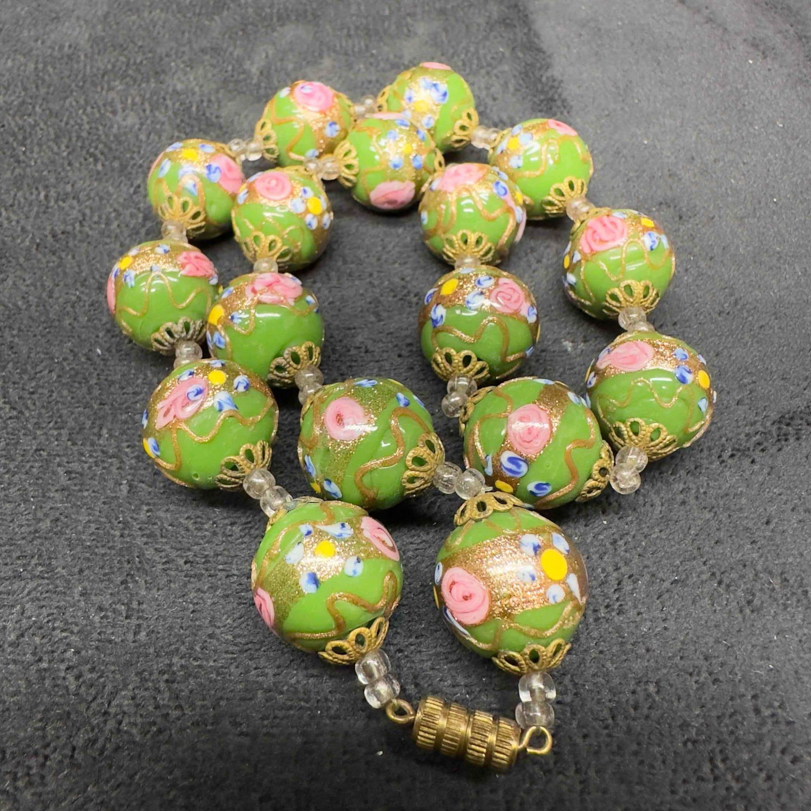 Venetian Murano Lamp Work Glass Green Bead Fiorato Floral Beaded Necklace A99: Venetian Murano Lamp Work Glass Green Bead Fiorato Floral Beaded Necklace A99. Necklace with green glass beads with beautiful floral designs on each. The necklace features copper colored accents. The