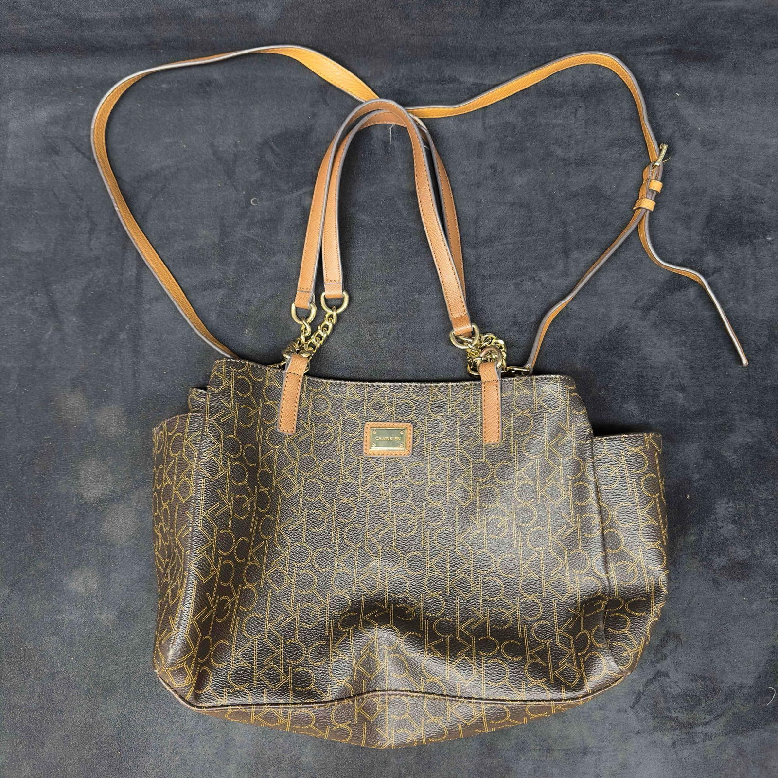 Calvin Klein Brown CK Signature Purse Handbag: Calvin Klein Brown CK Signature Purse Handbag . Calvin Klein handbag featuring a shoulder strap and handle. Eight pocket comparments for easy storage. Light stains noticed on the bag and on the interi