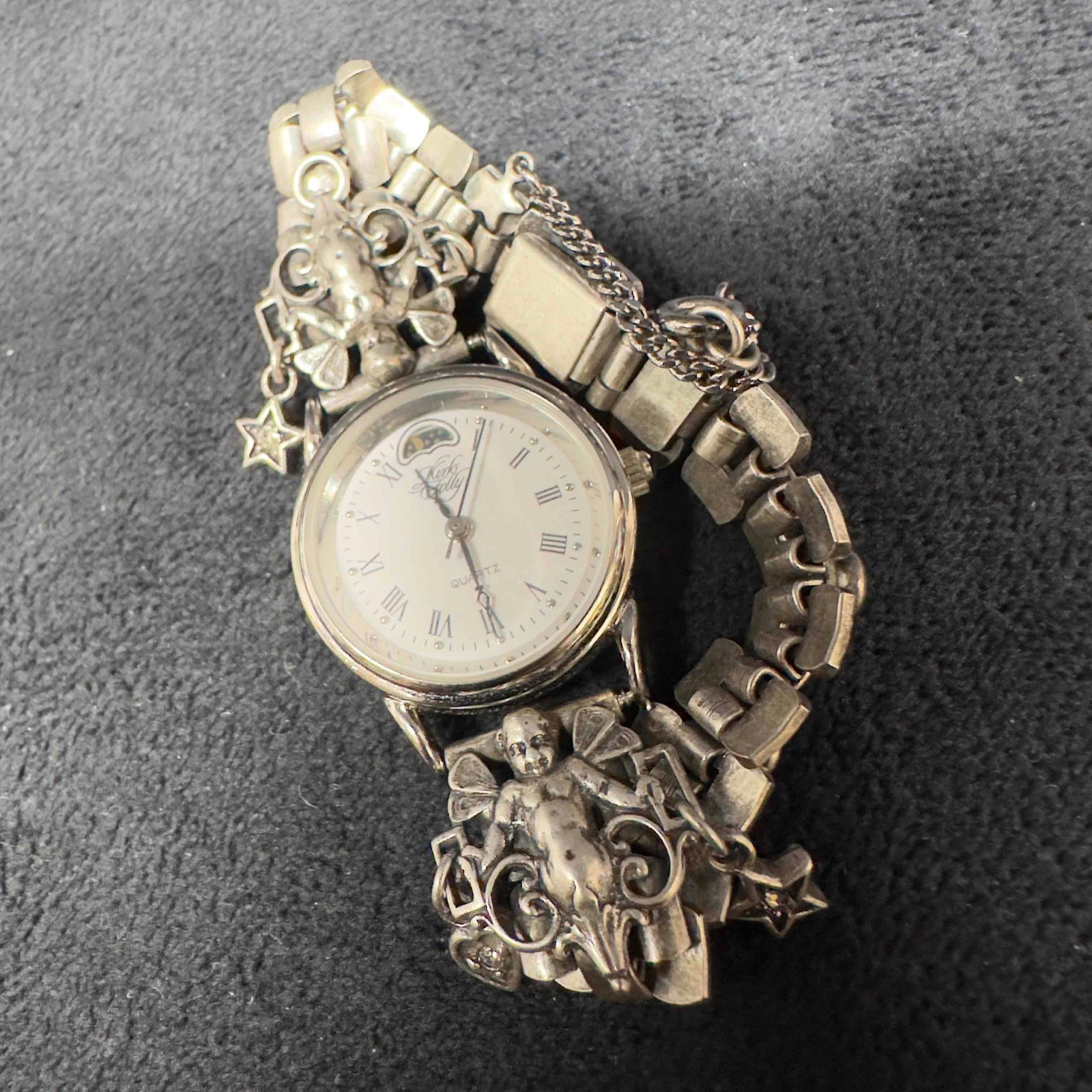 Kirks Folly Roman Numerals Angel Star Heart Moon Accents Watch K46Y: Kirks Folly Roman Numerals Angel Star Heart Moon Accents Watch K46Y. Etched Kirks Folly K46Y Hong Kong on the back of the watch. The watch features a buckle clasp closure and safety chain. Has not bee