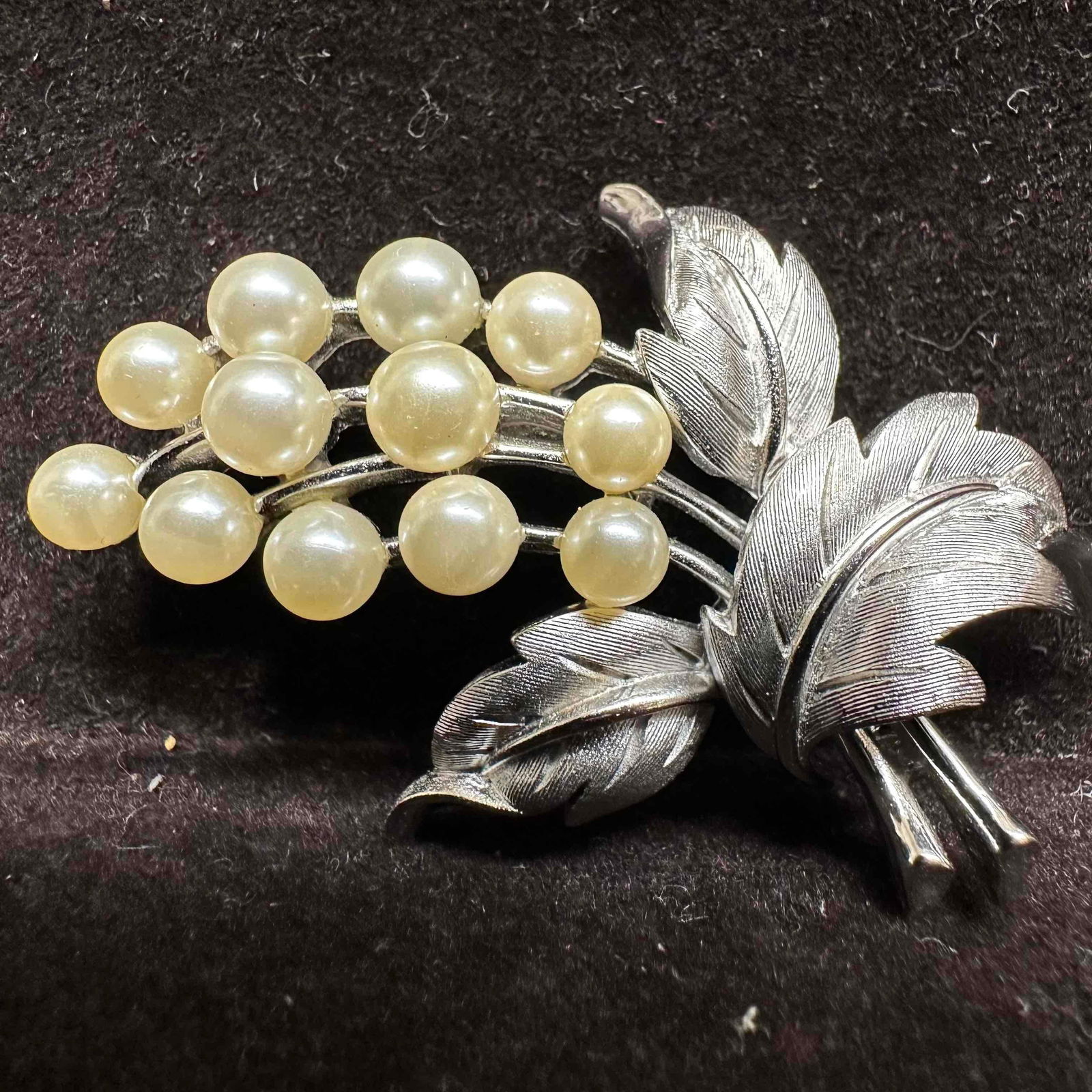 Crown Trifari Silver Tone Leaf Brooch with Faux Pearl Beads: Elegant vintage Trifari brooch featuring a silver tone leaf spray design adorned with clusters of round faux pearl beads. The textured metal leaves add detail and dimension. Marked "Trifari" o