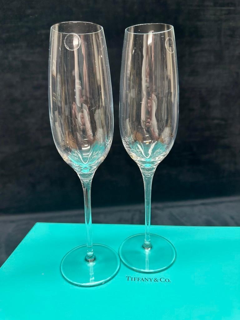 Tiffany & Co. Crystal Champagne Flutes: Set of two crystal champagne flutes by Tiffany & Co., made in Italy and elegantly engraved at the base with the Tiffany & Co. name. These premium-quality flutes are presented in their original