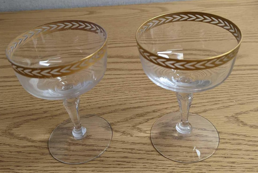 2 Vintage Fostoria Olympic Gold Trim Champagne Glasses: 2 Vintage Fostoria Olympic Gold Trim Champagne Glasses. Each glass is approx 3 3/4" x 3 3/4" x 5 1/4" and together they weigh 0.77lb. The glasses are in a good, vintage condition with some
